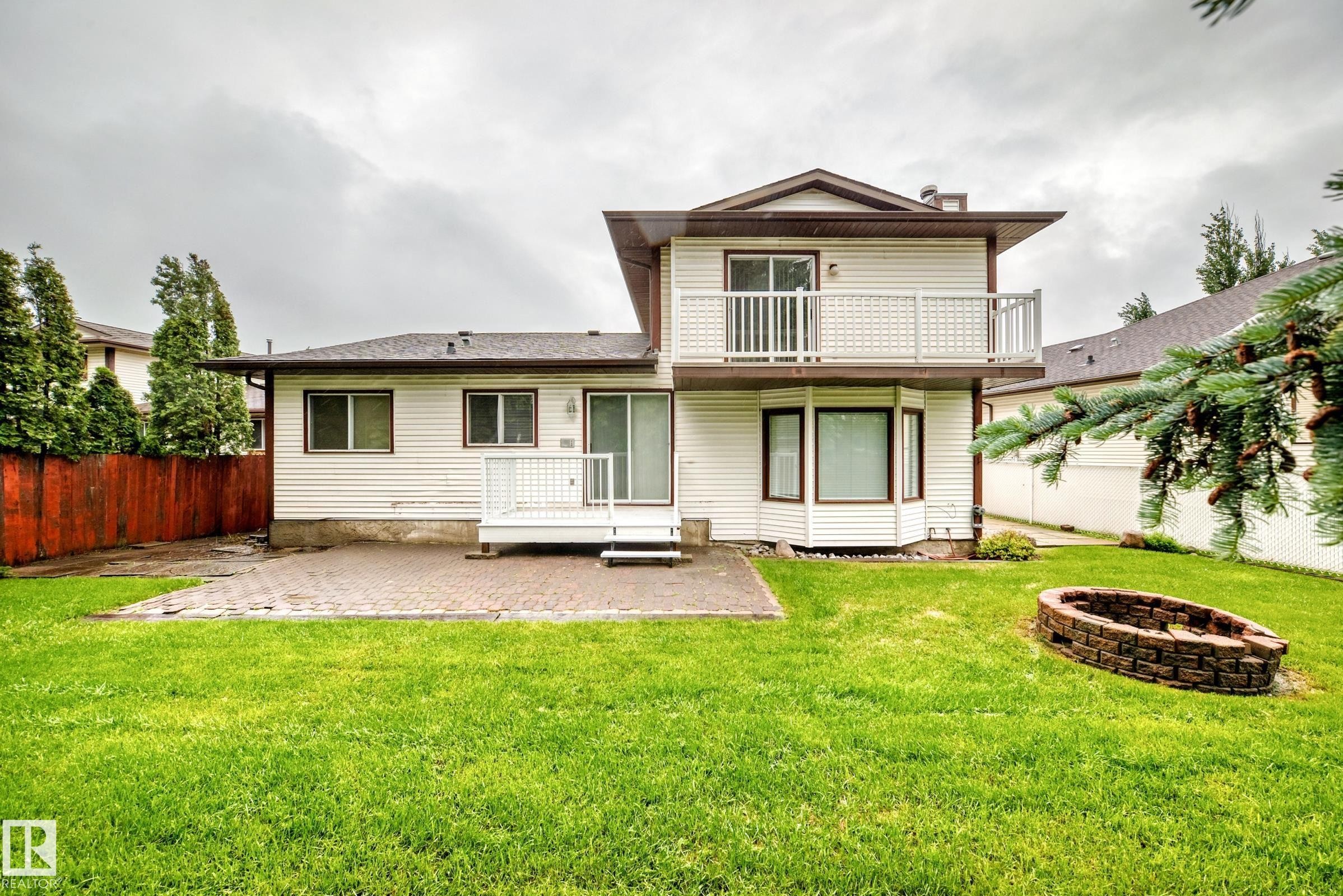Rear exterior with a two-story design featuring a private upper balcony, ground-level deck, and a bay window - 9843 188 Street, Edmonton, AB