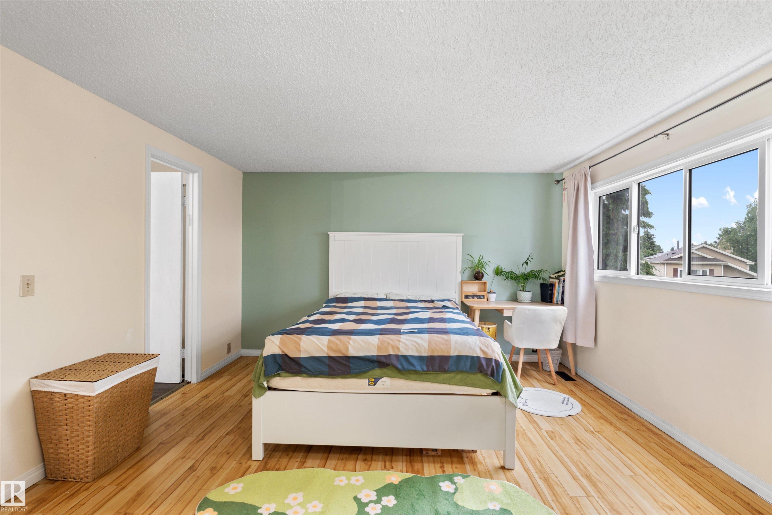 Room featuring wood-finish flooring, a painted accent wall, and multiple windows - 359 Kirkpatrick Crescent, Edmonton, AB