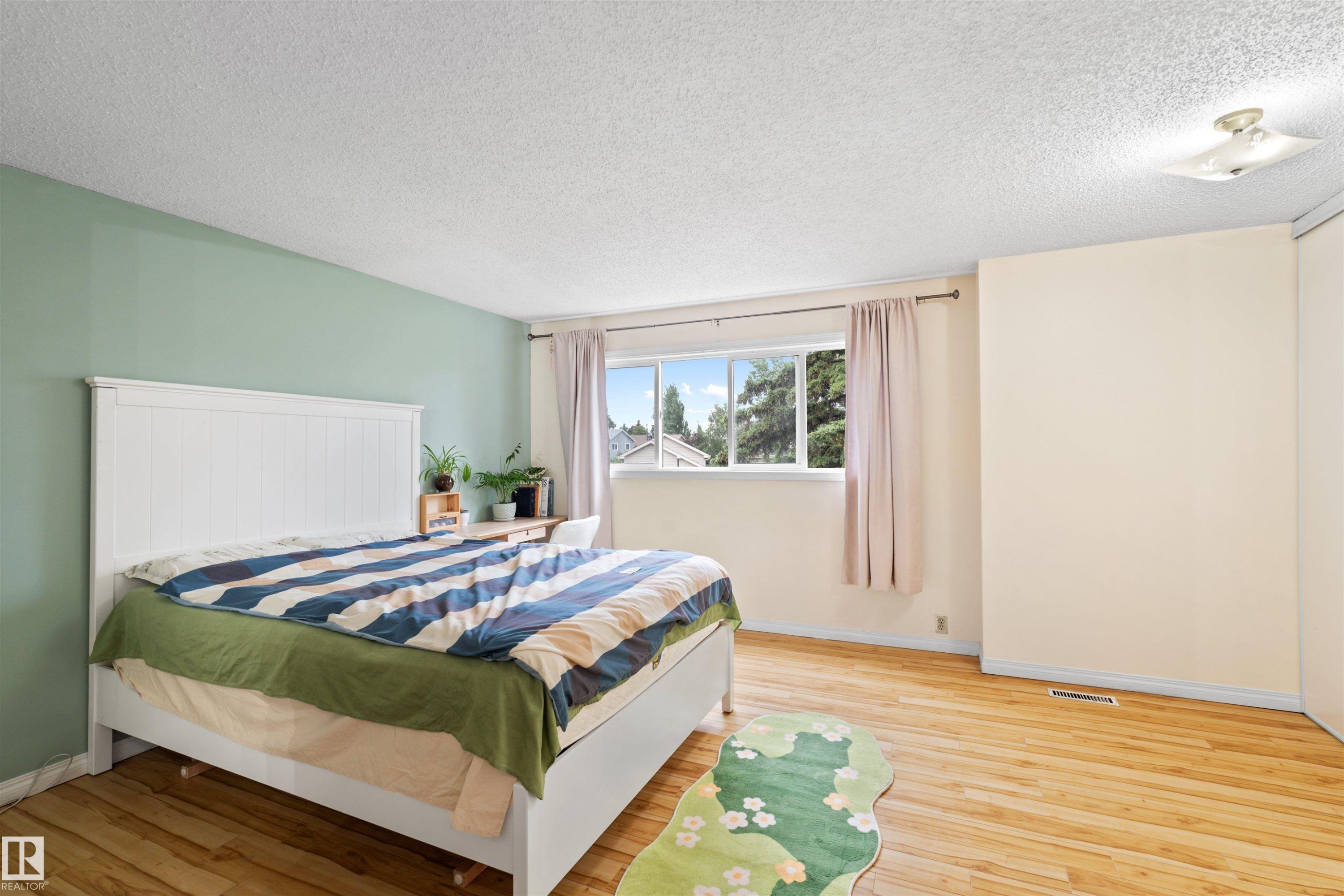 Bright interior space featuring wood-finish flooring, a window offering exterior views, a ceiling-mounted light fixture, and walls finished in a two-tone color scheme - 359 Kirkpatrick Crescent, Edmonton, AB