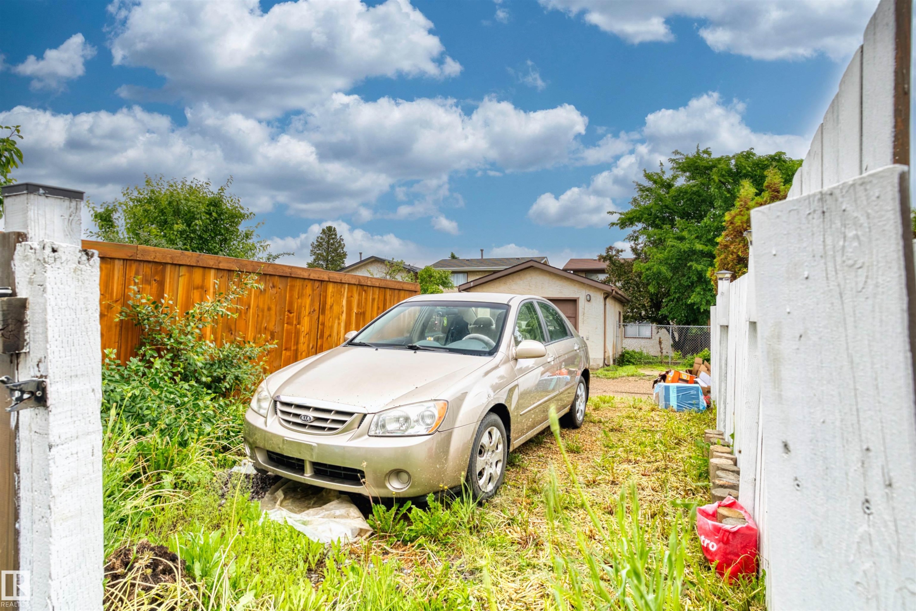 White wood fence framing a gravel side yard with a detached garage - 359 Kirkpatrick Crescent, Edmonton, AB