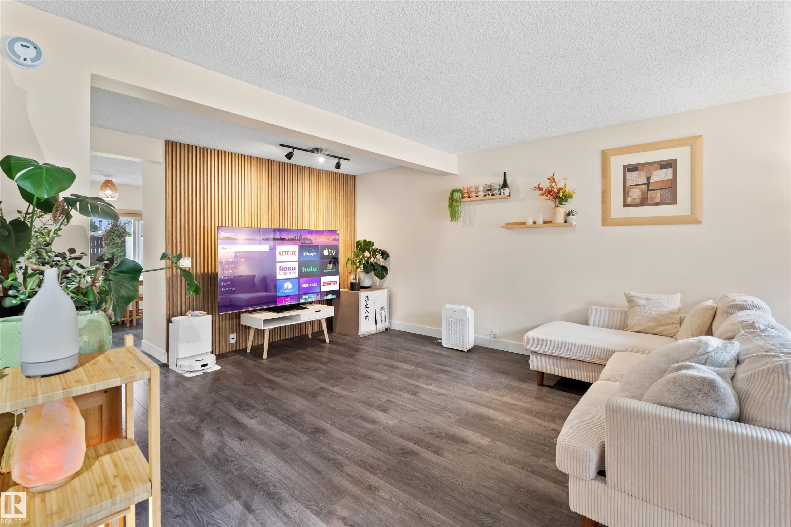 Spacious living area featuring modern wood-finish flooring, a contemporary slat wall accent, and recessed track lighting - 359 Kirkpatrick Crescent, Edmonton, AB
