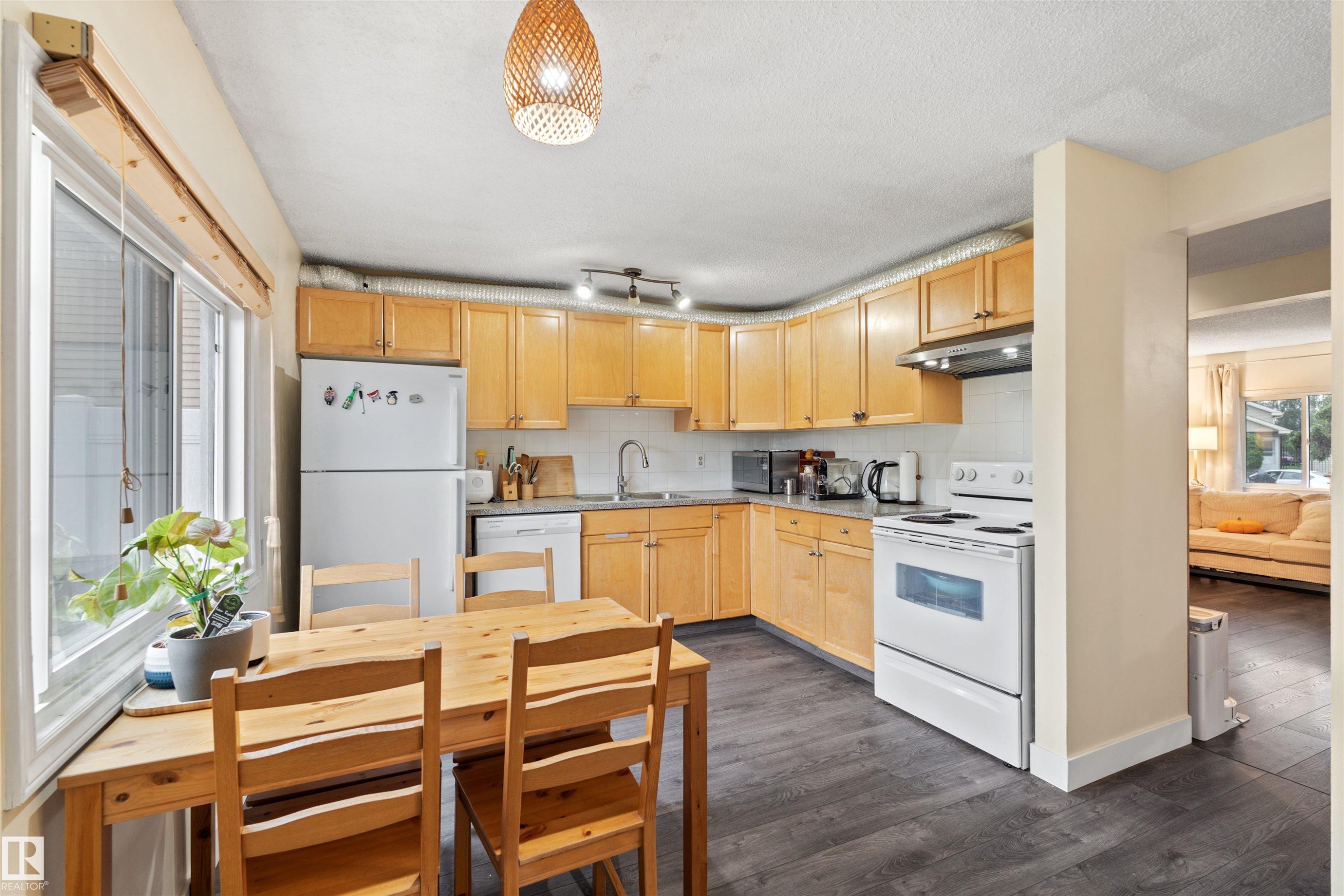 U-shaped kitchen featuring wood cabinetry, dark wood-finish flooring, a white range, a white refrigerator, and a recessed sink with a white tiled backsplash - 359 Kirkpatrick Crescent, Edmonton, AB