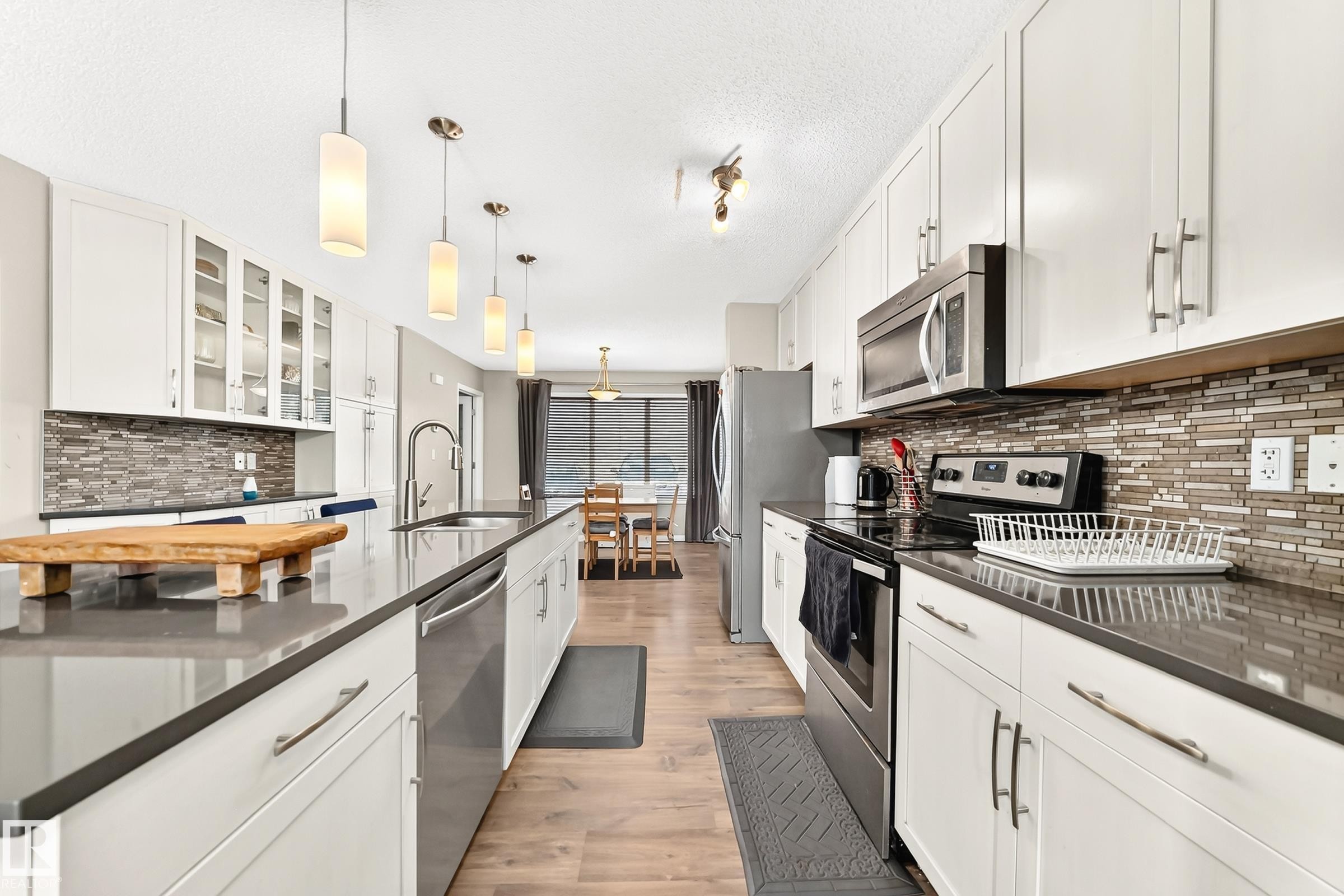 Modern kitchen featuring an extended island with a built-in sink and pendant lighting - 875 Chappelle Link Link Sw, Edmonton, AB