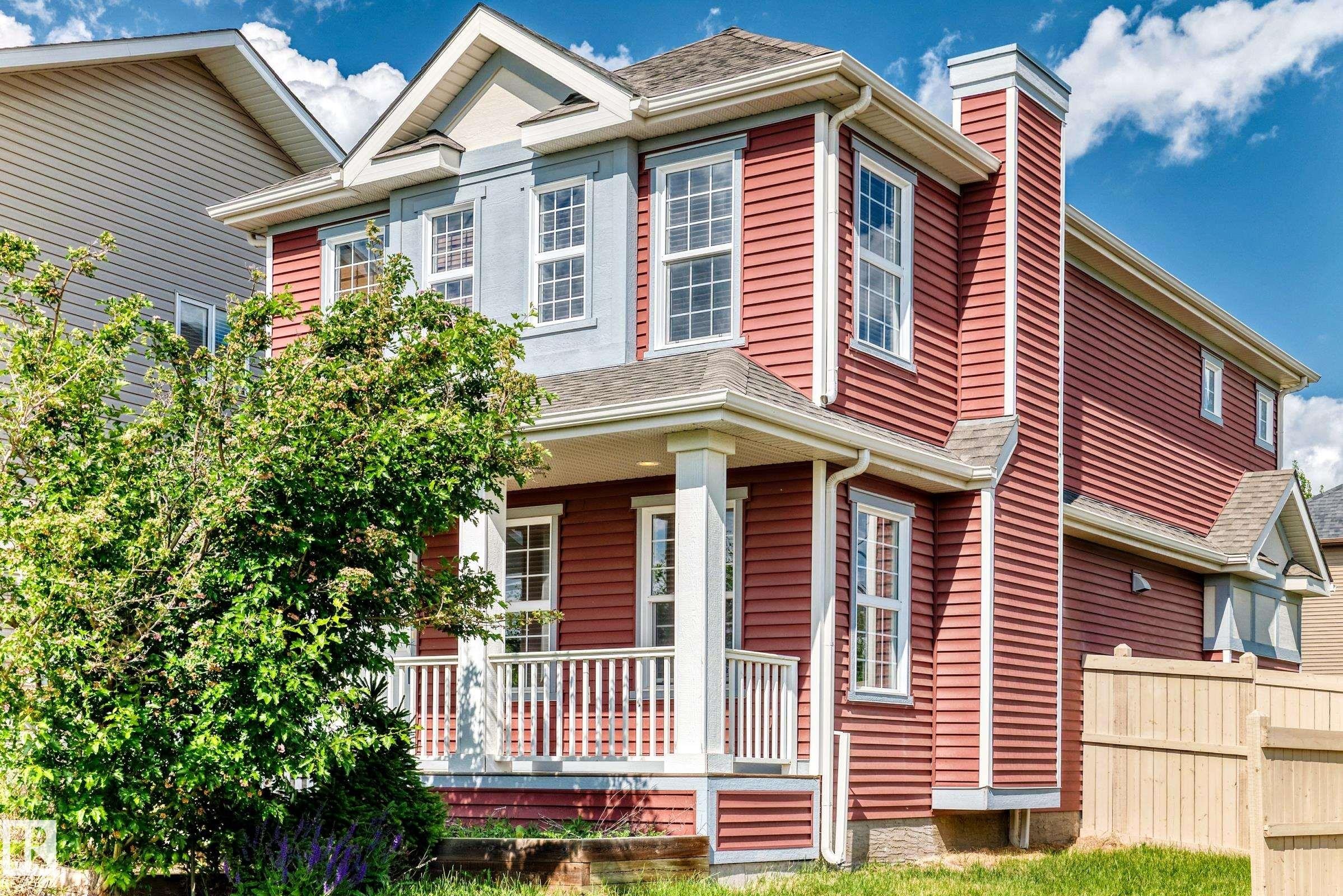 Two-story residence featuring red horizontal siding, light blue stucco accents, and multiple dormer windows - 875 Chappelle Link Link Sw, Edmonton, AB