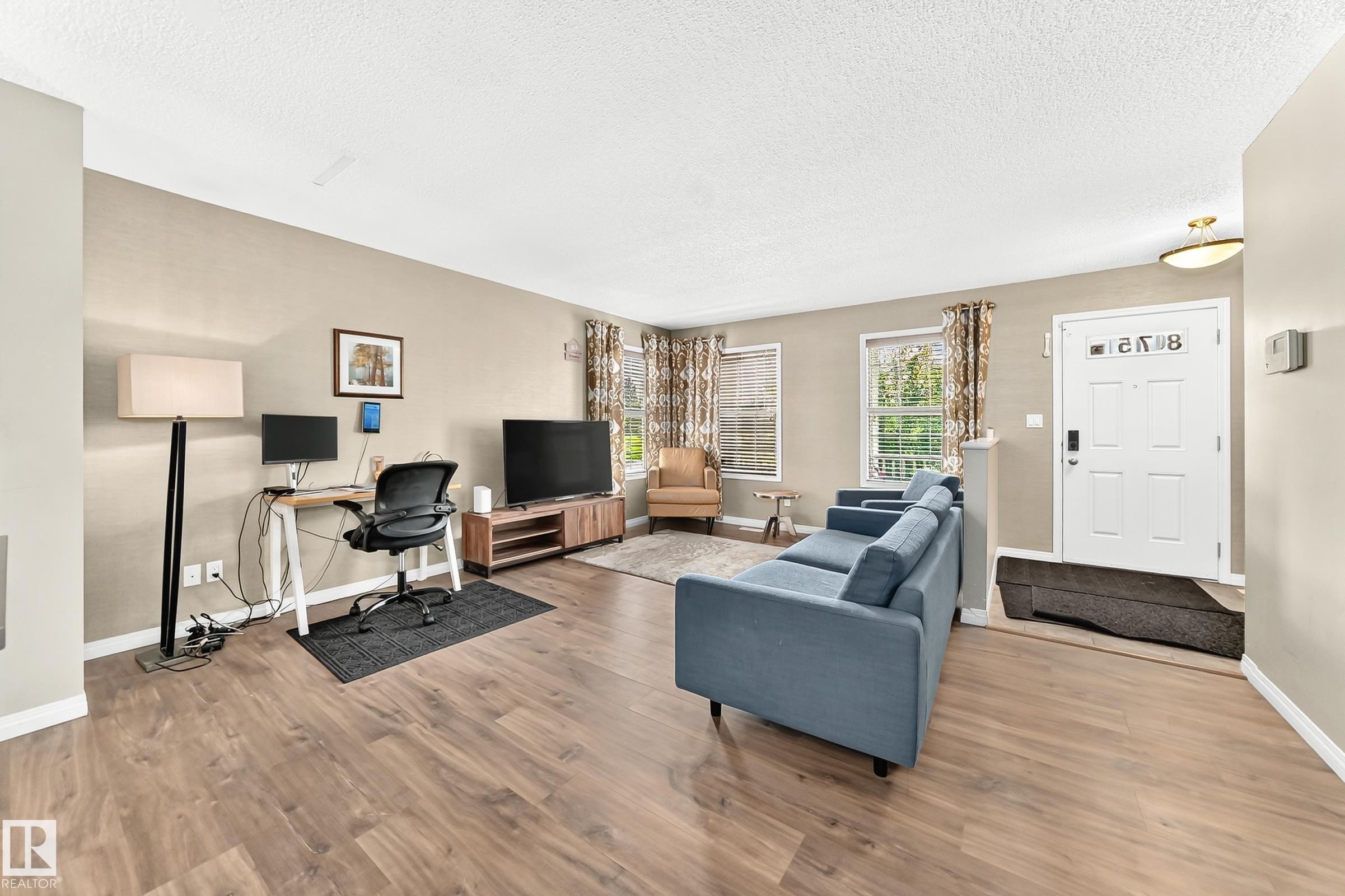 Open-concept living space with wood-finish flooring, neutral wall tones, and multiple windows - 875 Chappelle Link Link Sw, Edmonton, AB