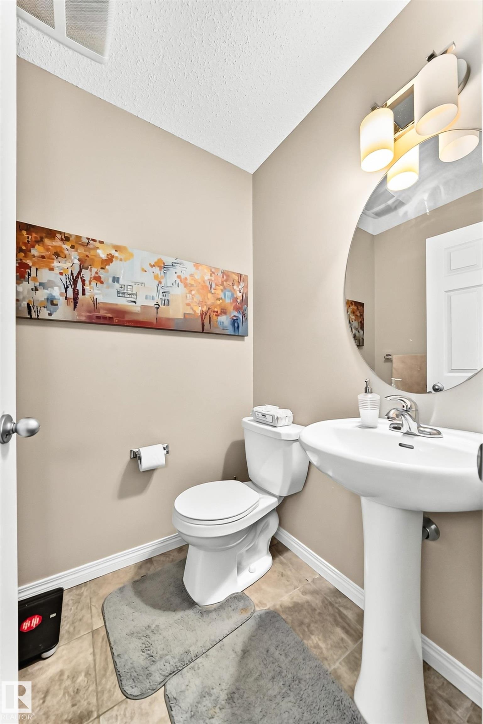 Powder room featuring a pedestal sink, round mirror, and tile flooring - 875 Chappelle Link Link Sw, Edmonton, AB