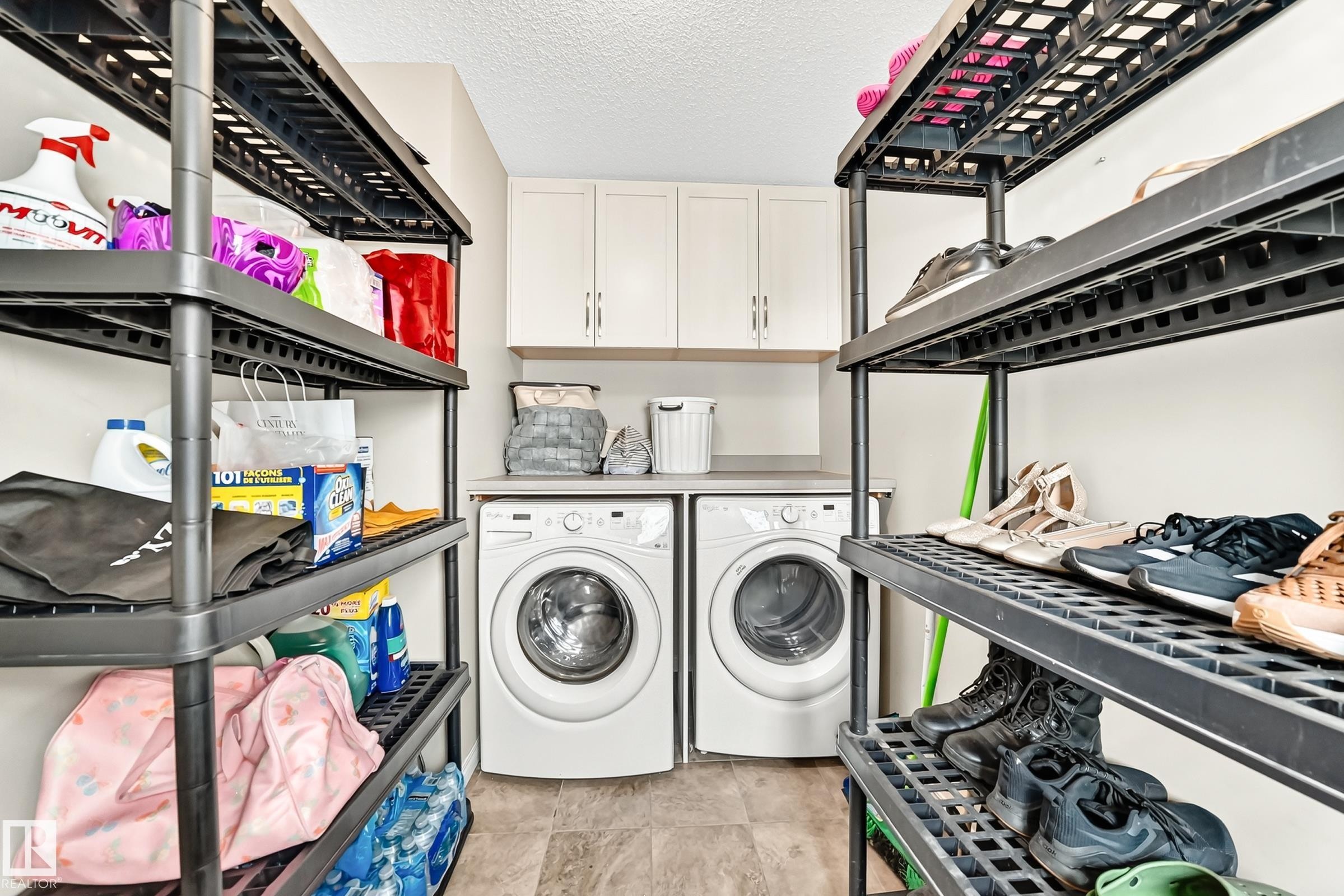 Dedicated laundry area featuring a side-by-side washer and dryer, light-toned countertop, and upper cabinetry - 875 Chappelle Link Link Sw, Edmonton, AB