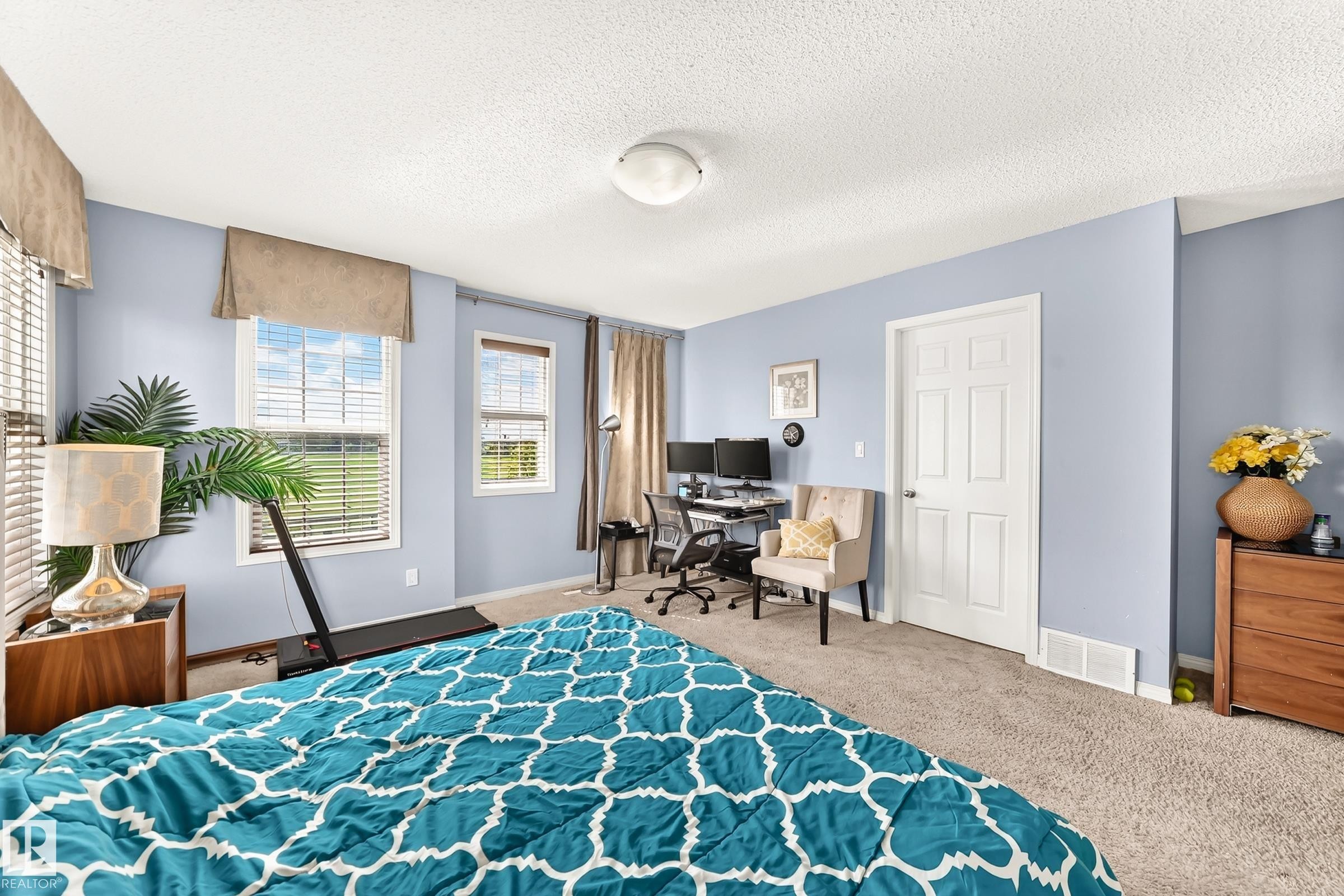 Spacious room featuring light blue walls, multiple white-trimmed windows with blinds, a white paneled door, and neutral carpet flooring - 875 Chappelle Link Link Sw, Edmonton, AB