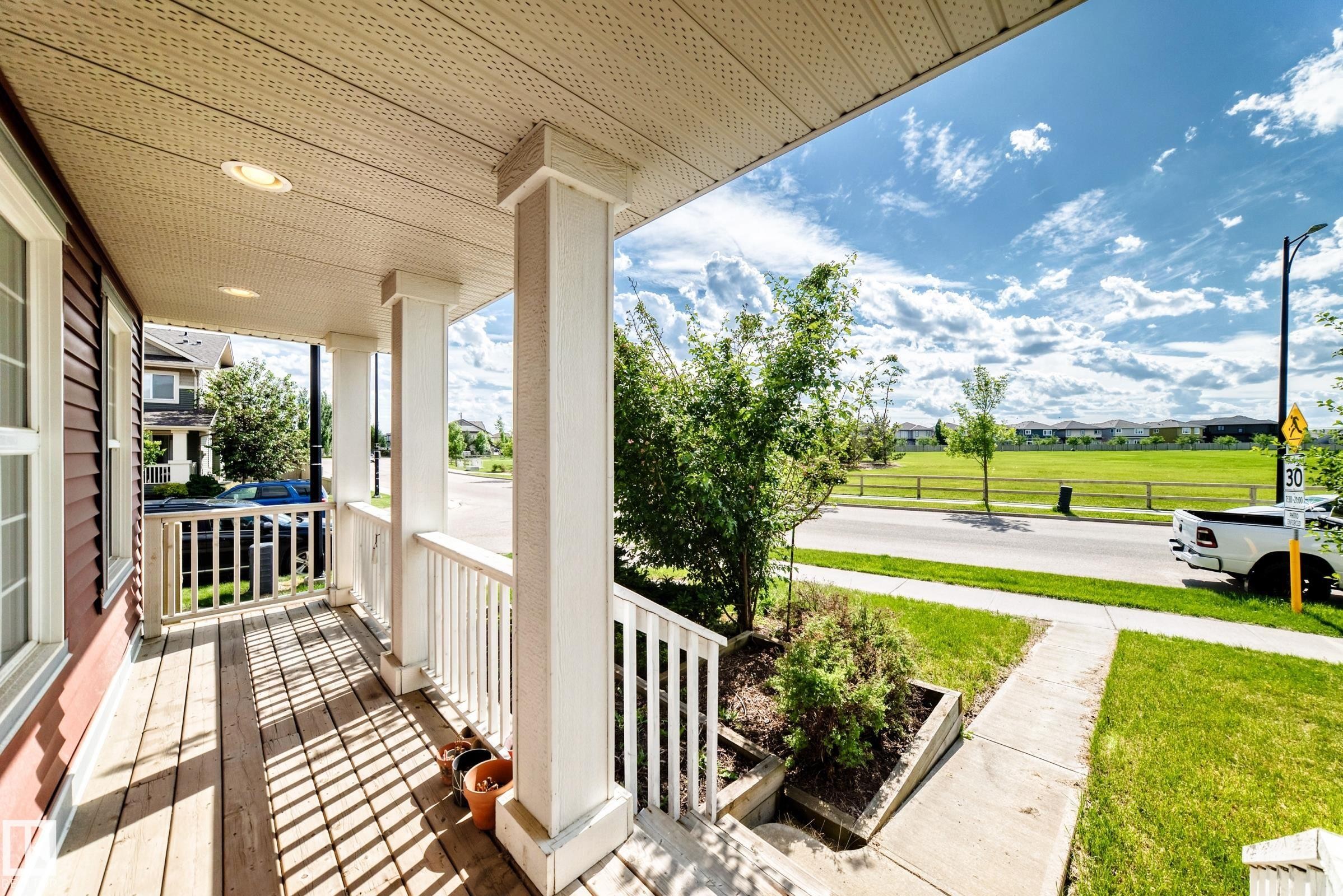 Covered front porch with wood-finish flooring and white railings - 875 Chappelle Link Link Sw, Edmonton, AB