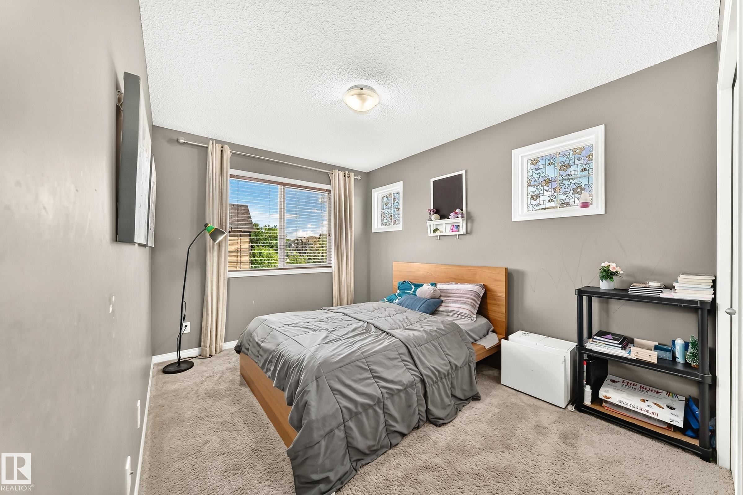 Carpeted bedroom with a single window featuring horizontal blinds and light-colored drapes - 875 Chappelle Link Link Sw, Edmonton, AB