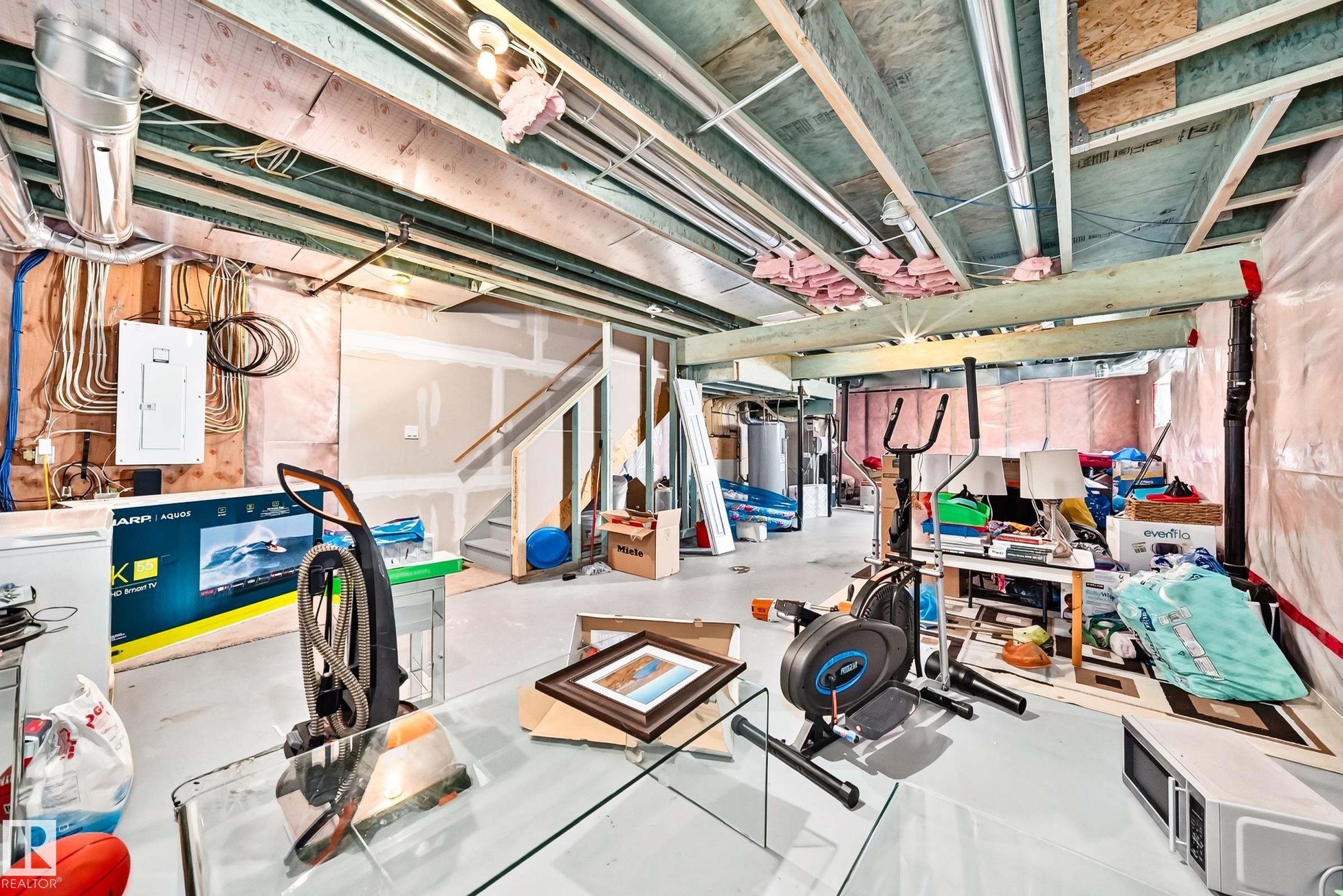 Unfinished basement offering exposed ceiling joists and framing, a built-in staircase, and a visible electrical panel - 875 Chappelle Link Link Sw, Edmonton, AB