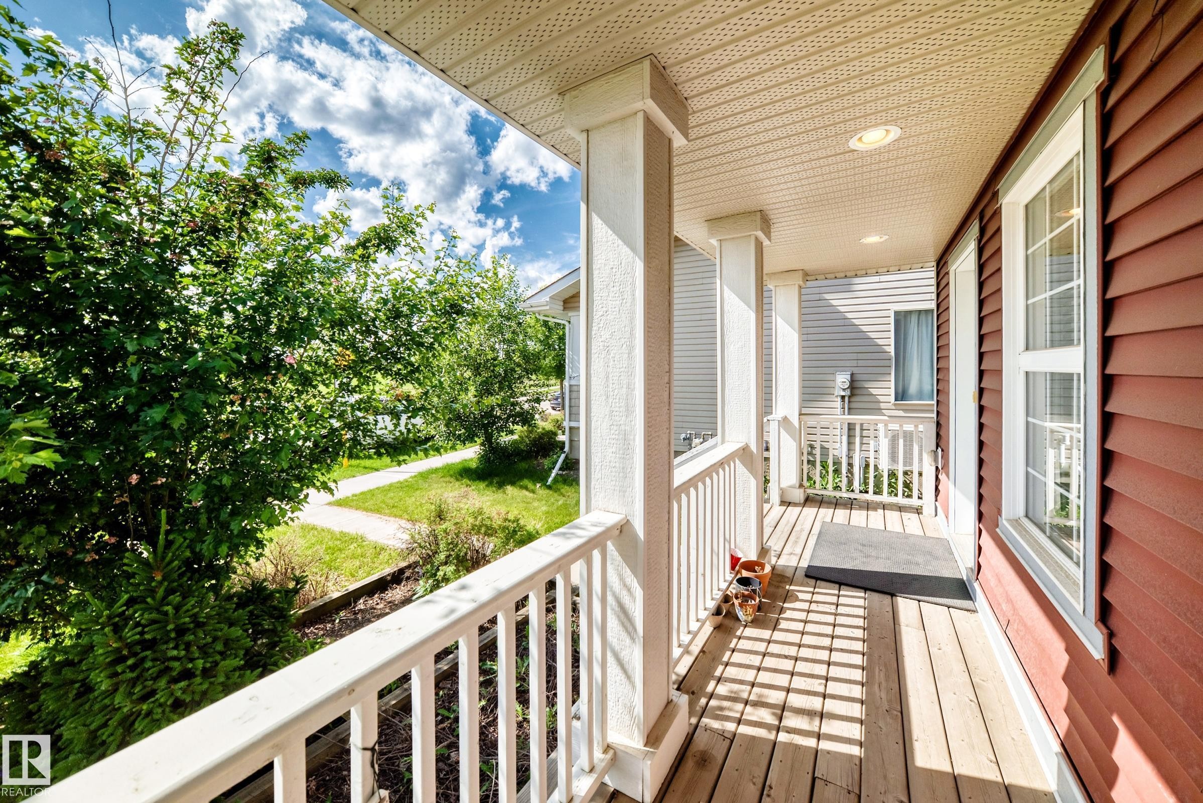 Covered porch with wood-finish flooring and white railings - 875 Chappelle Link Link Sw, Edmonton, AB