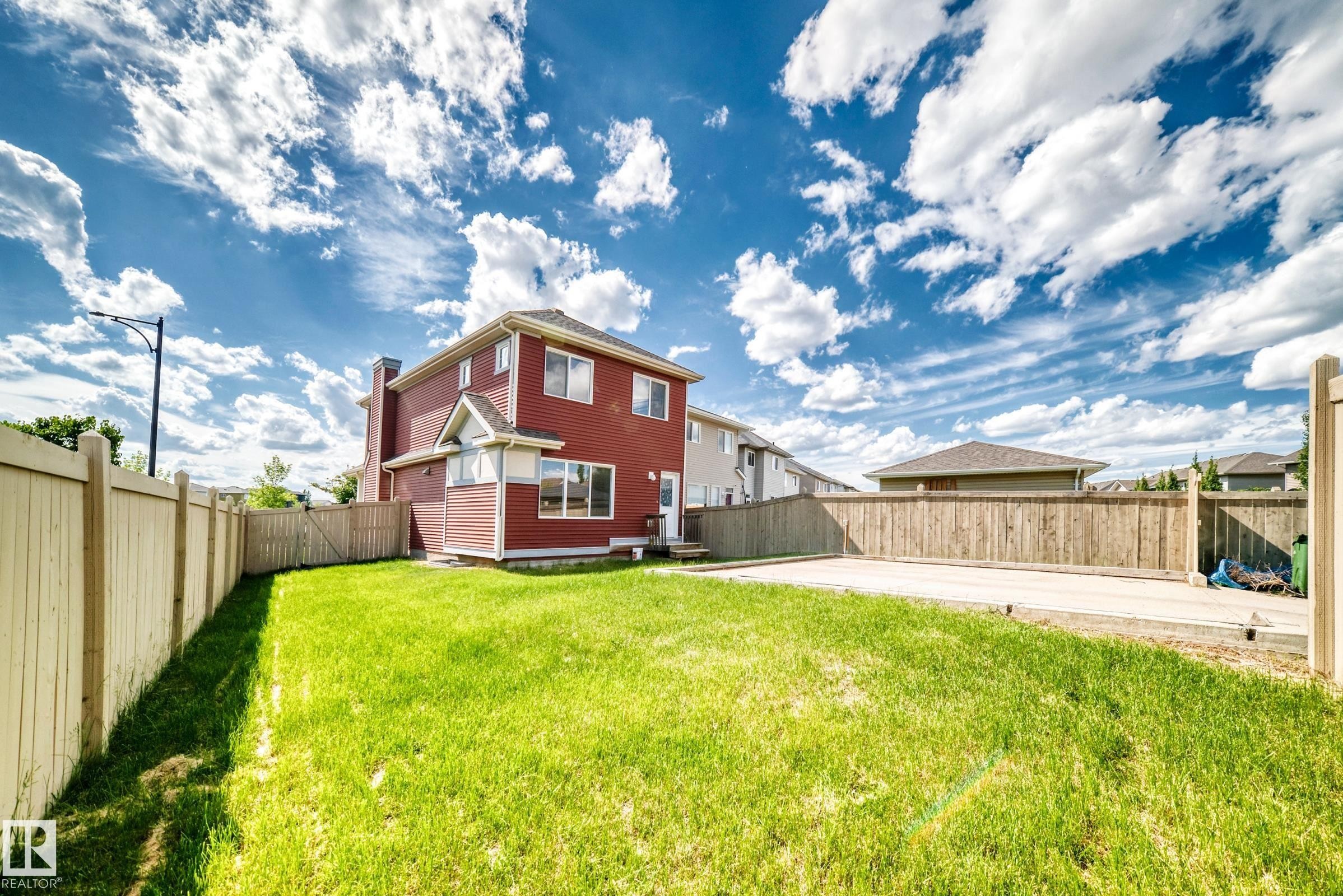Spacious backyard featuring a large grass area, wood privacy fencing, and a concrete pad - 875 Chappelle Link Link Sw, Edmonton, AB