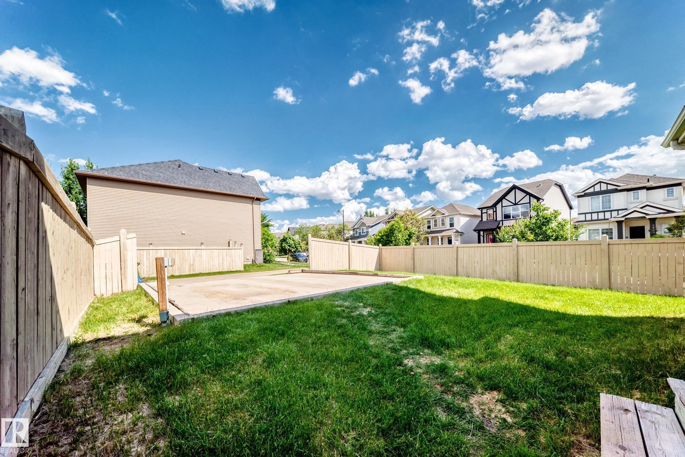 Expansive backyard featuring a large concrete pad, established lawn, and full privacy fencing - 875 Chappelle Link Link Sw, Edmonton, AB