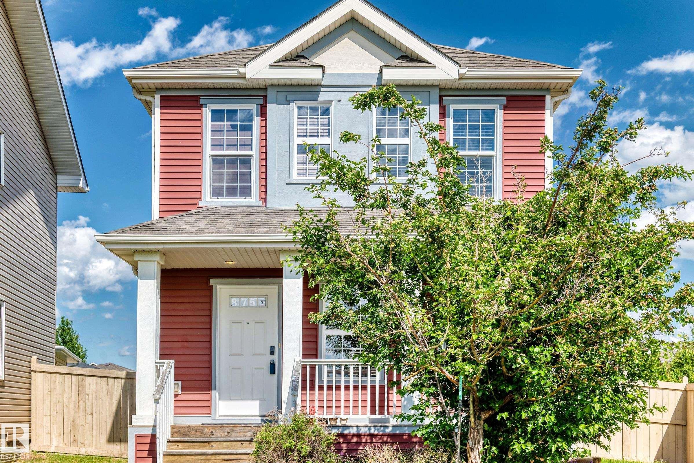 Two-story property featuring red and light blue siding, a covered front porch with white railings, and a prominent front-facing gable - 875 Chappelle Link Link Sw, Edmonton, AB