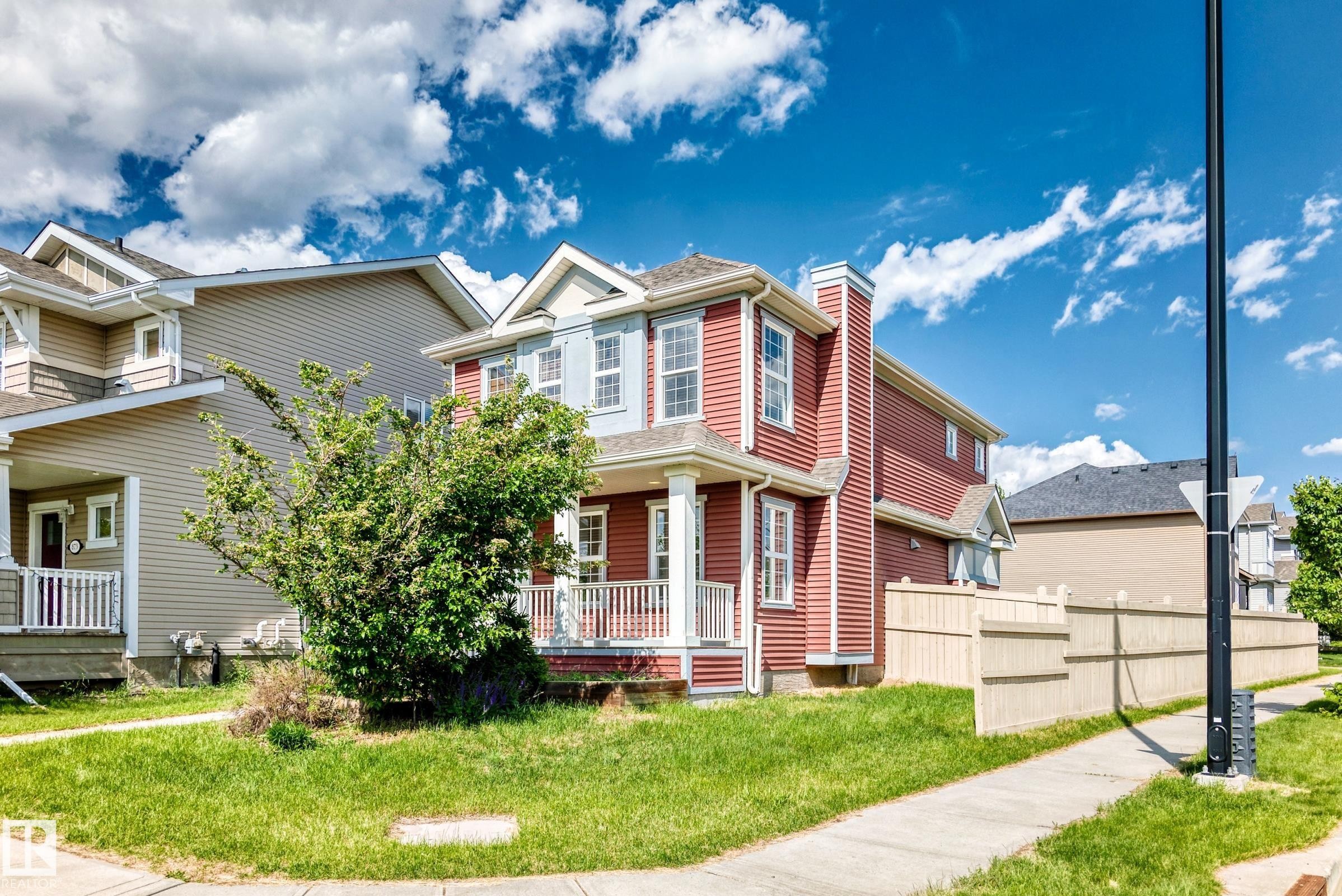 Red siding exterior with white trim accents and a covered front porch featuring white railings - 875 Chappelle Link Link Sw, Edmonton, AB