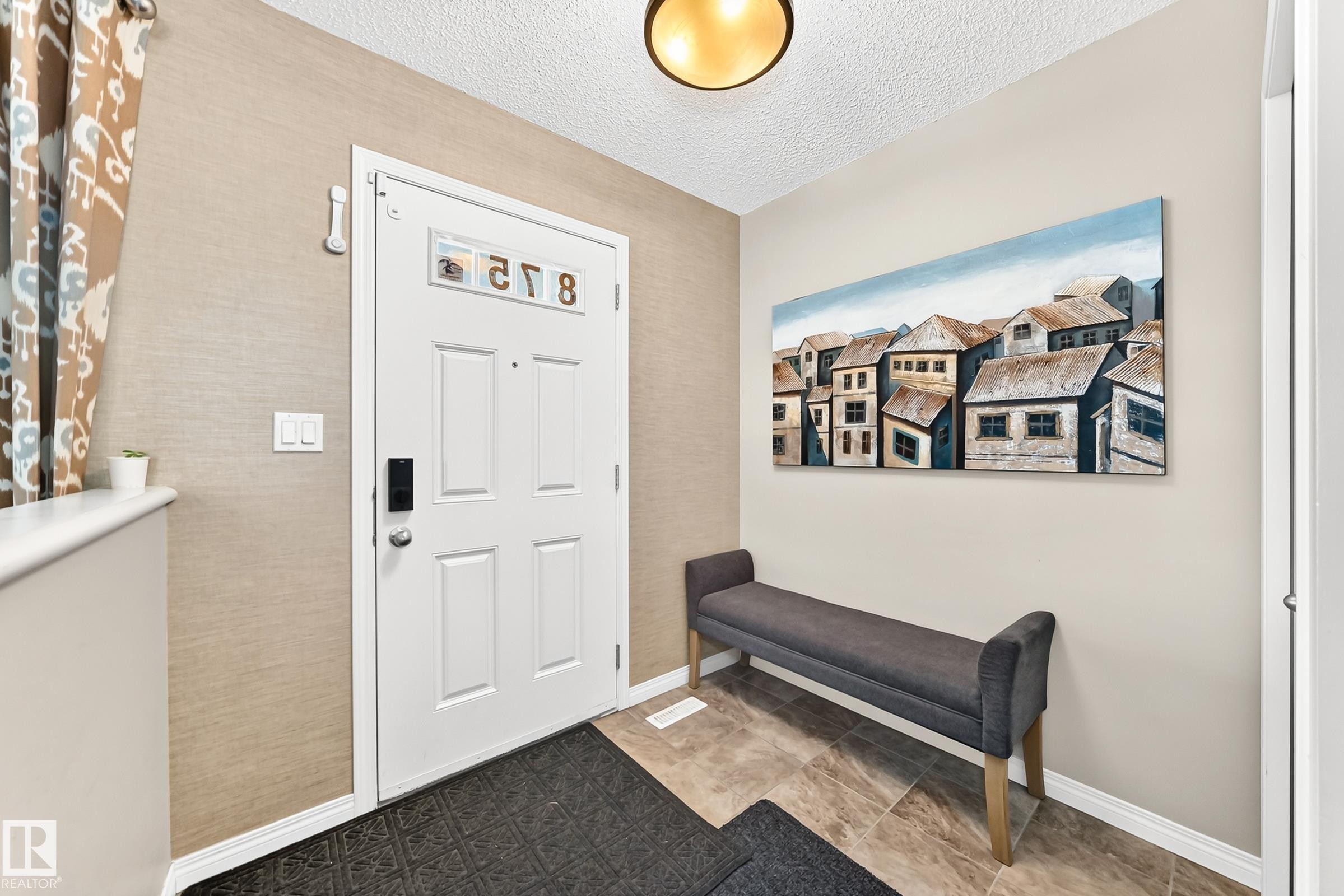 Entryway featuring a white paneled door, textured wall covering, and a ceiling-mounted light fixture - 875 Chappelle Link Link Sw, Edmonton, AB
