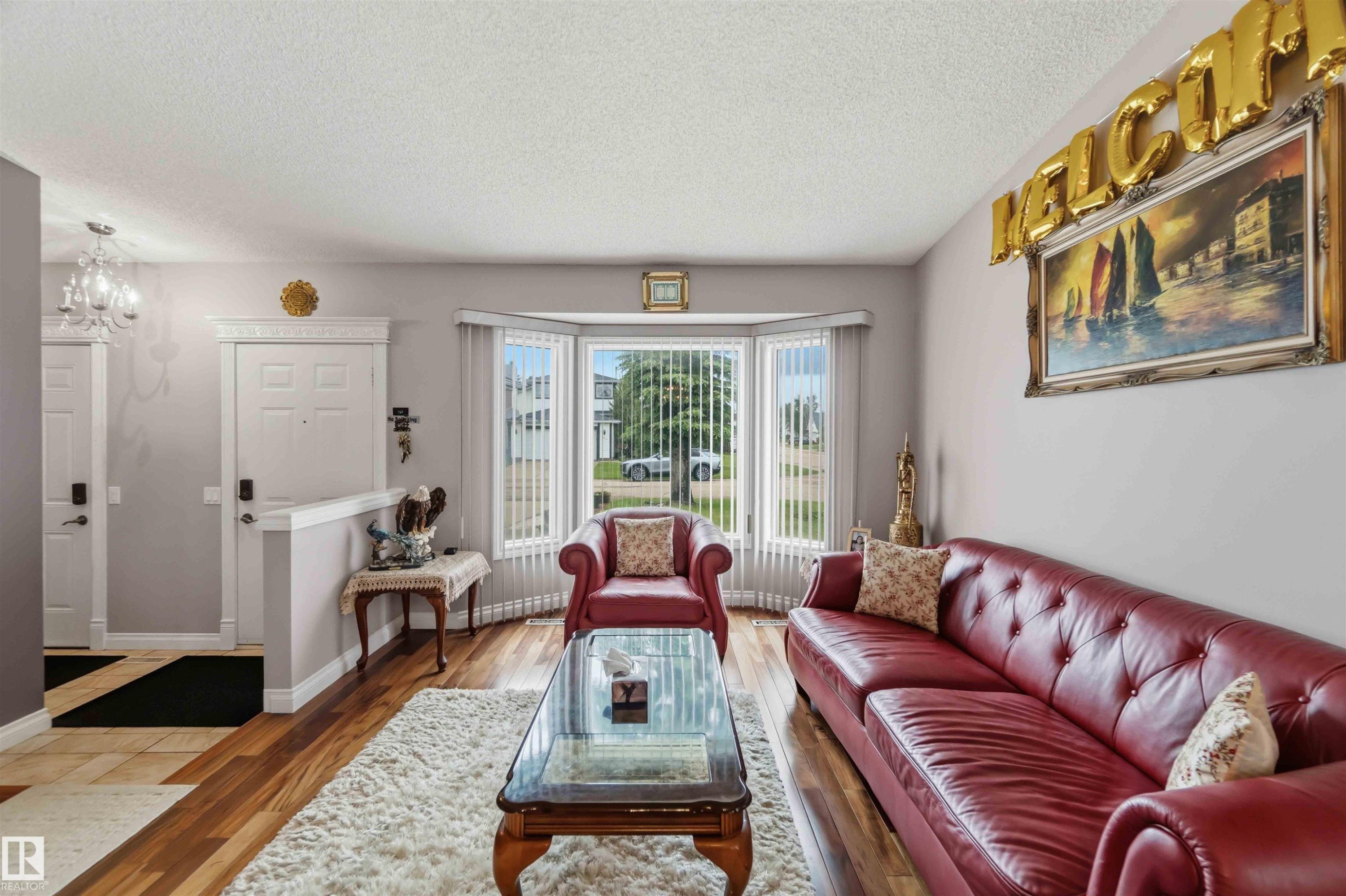 Living area featuring a bay window, wood-finish flooring, and a crystal-style chandelier at the entry - 4428 11A Avenue Nw, Edmonton, AB - Indoor Photo Showing Living Room