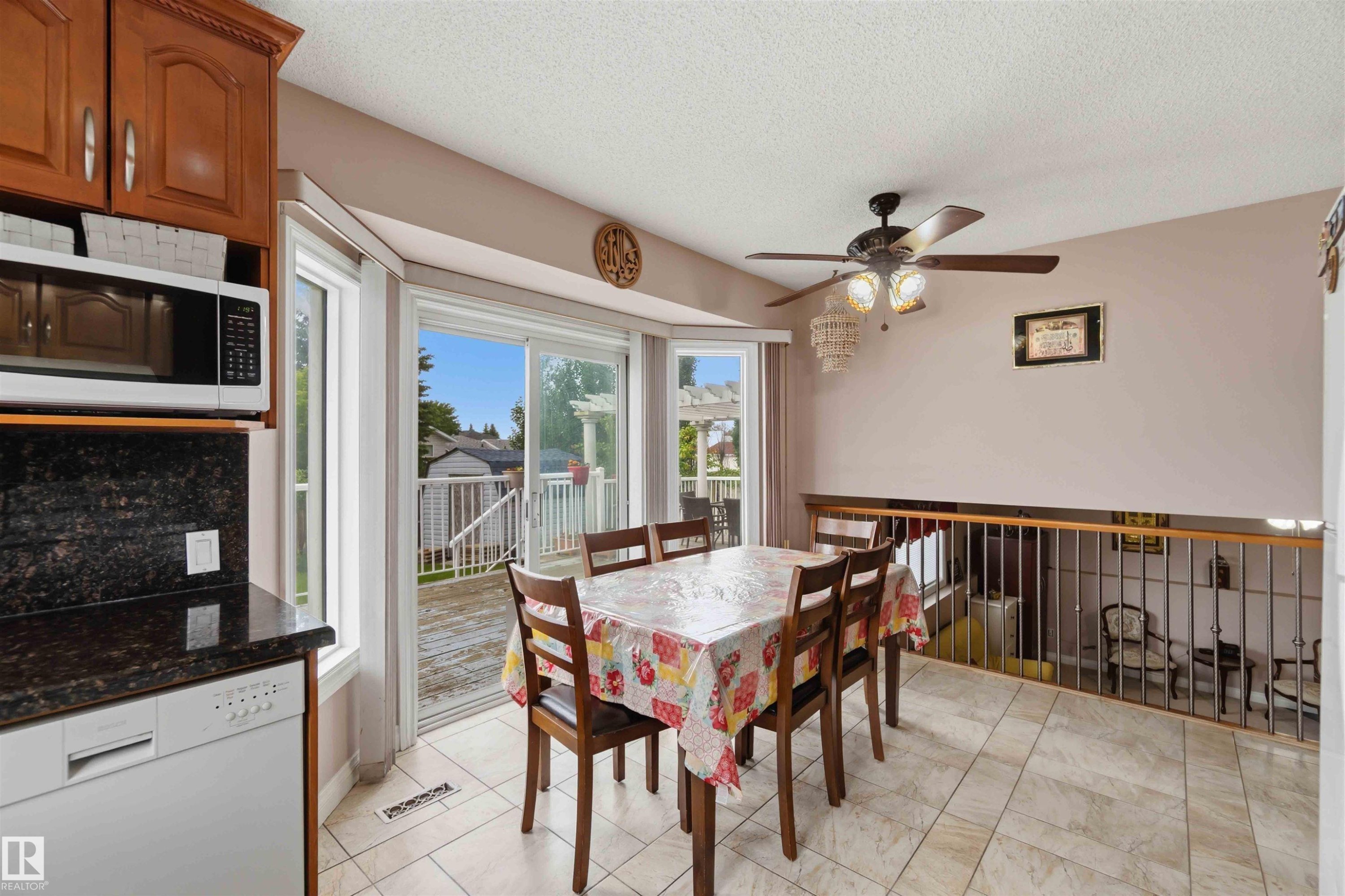 Kitchen and dining area featuring a built-in microwave, dark granite-look countertops, and a white dishwasher - 4428 11A Avenue Nw, Edmonton, AB - Indoor Photo Showing Dining Room