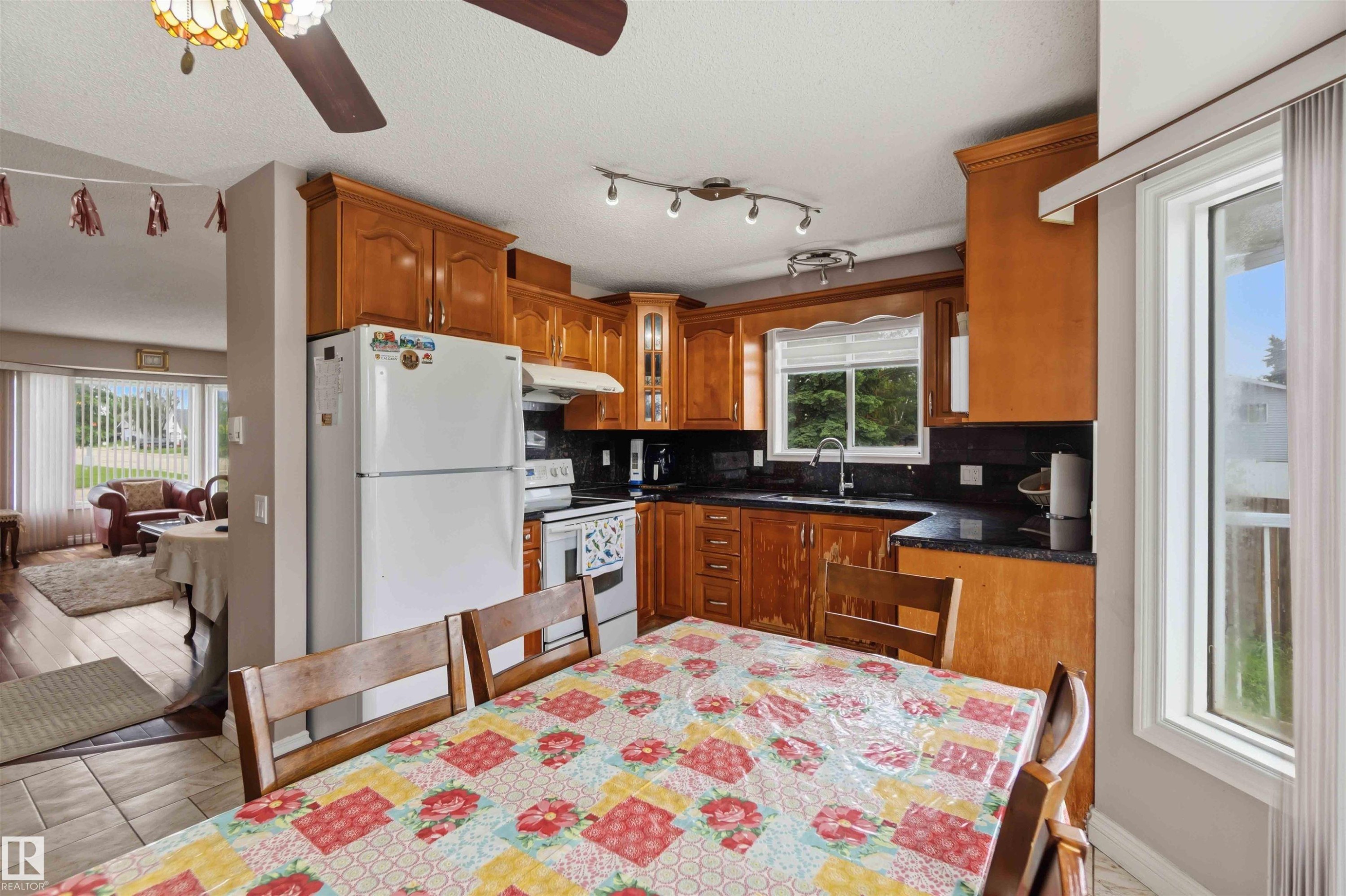 Kitchen featuring wood cabinetry, black countertops, and a stainless steel sink - 4428 11A Avenue Nw, Edmonton, AB - Indoor