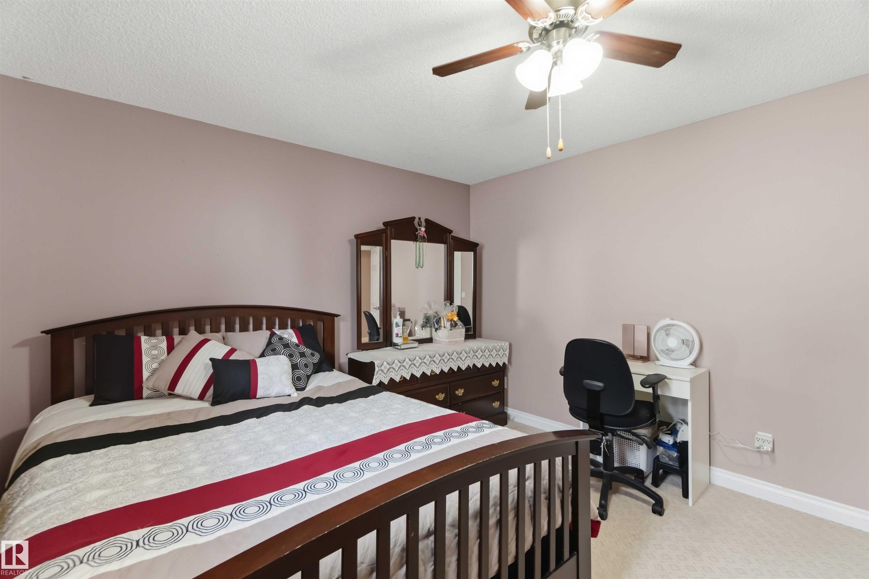 Carpeted bedroom featuring a ceiling fan with integrated lighting, neutral wall tones, and white baseboards - 4428 11A Avenue Nw, Edmonton, AB - Indoor Photo Showing Bedroom