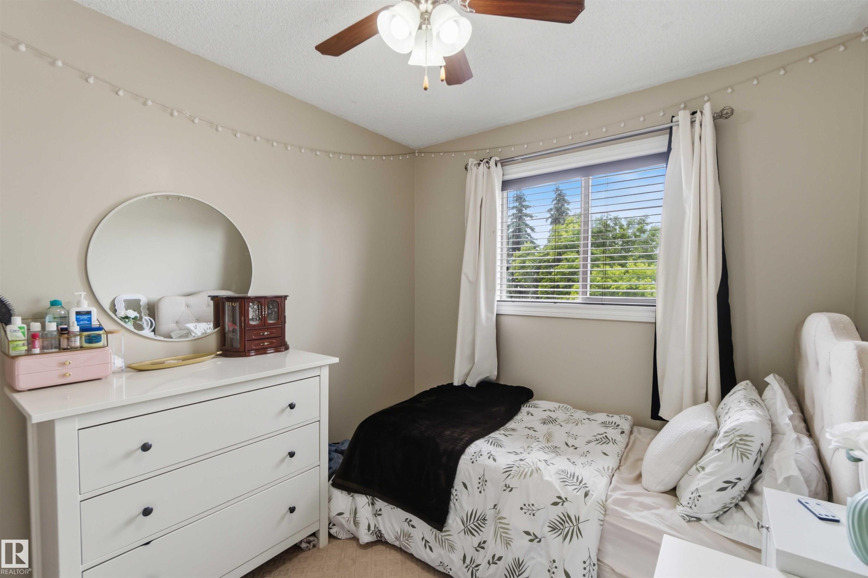 Bedroom featuring a single window with blinds and curtains, a ceiling fan with integrated lighting, and neutral wall tones - 4428 11A Avenue Nw, Edmonton, AB - Indoor Photo Showing Bedroom