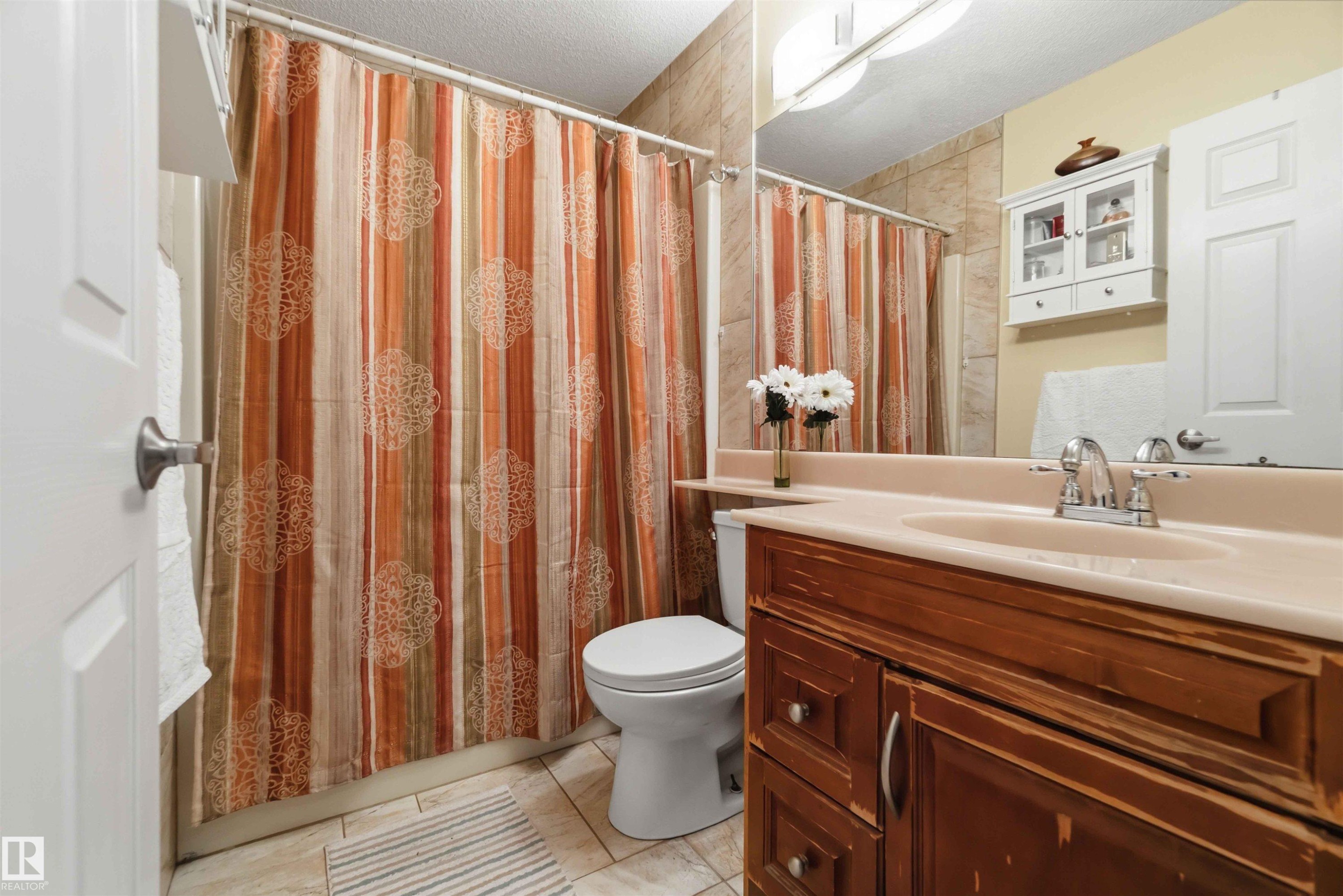 Full bathroom featuring a wood-finish vanity with an integrated sink, polished chrome faucet, and a wall-mounted medicine cabinet - 4428 11A Avenue Nw, Edmonton, AB - Indoor Photo Showing Bathroom