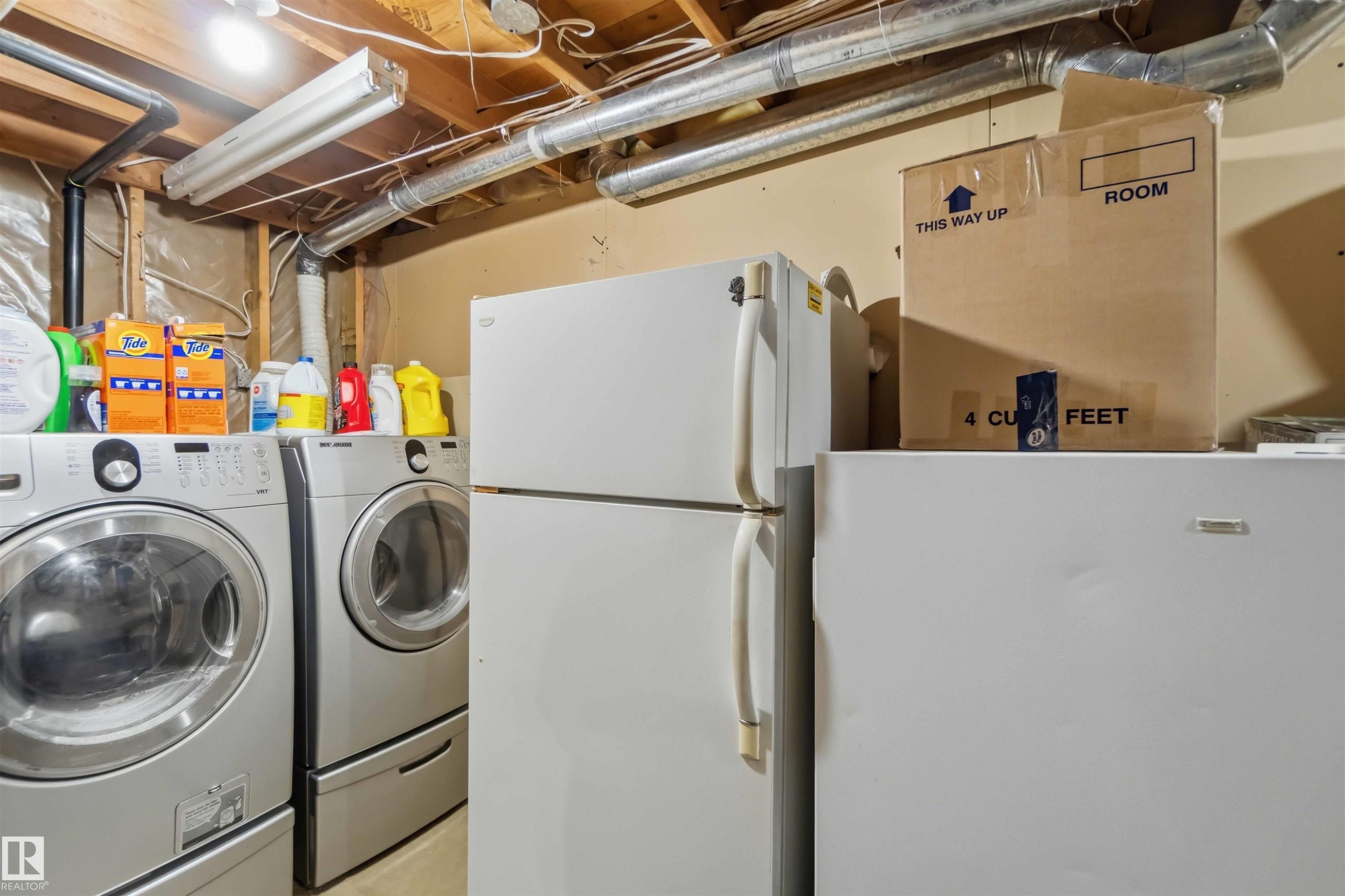 Dedicated laundry area featuring a front-loading washer and dryer with pedestal bases - 4428 11A Avenue Nw, Edmonton, AB - Indoor Photo Showing Laundry Room