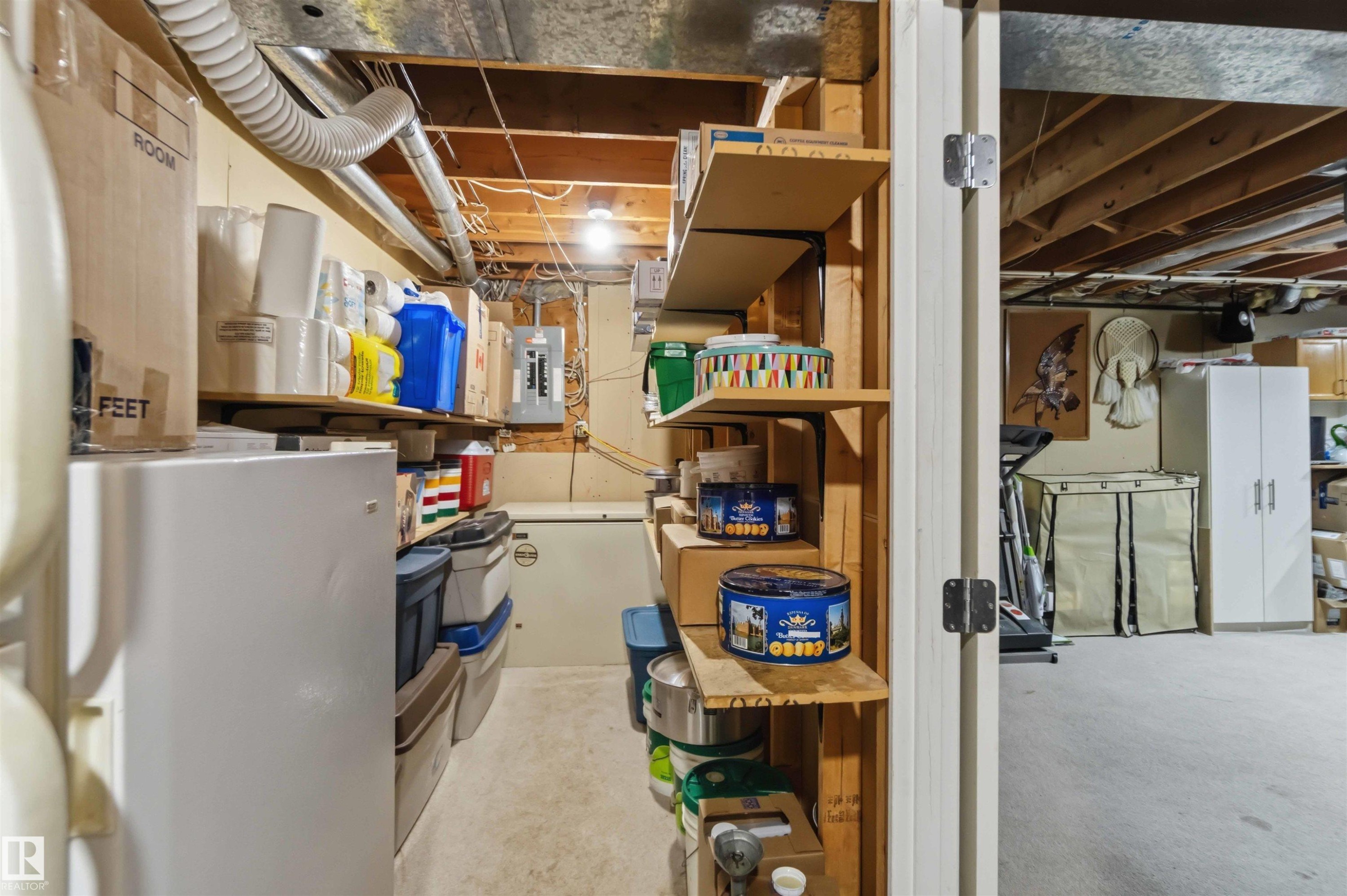 Utility area featuring exposed ceiling joists, overhead lighting, built-in shelving, a dedicated electrical panel, and concrete flooring - 4428 11A Avenue Nw, Edmonton, AB - Indoor Photo Showing Basement