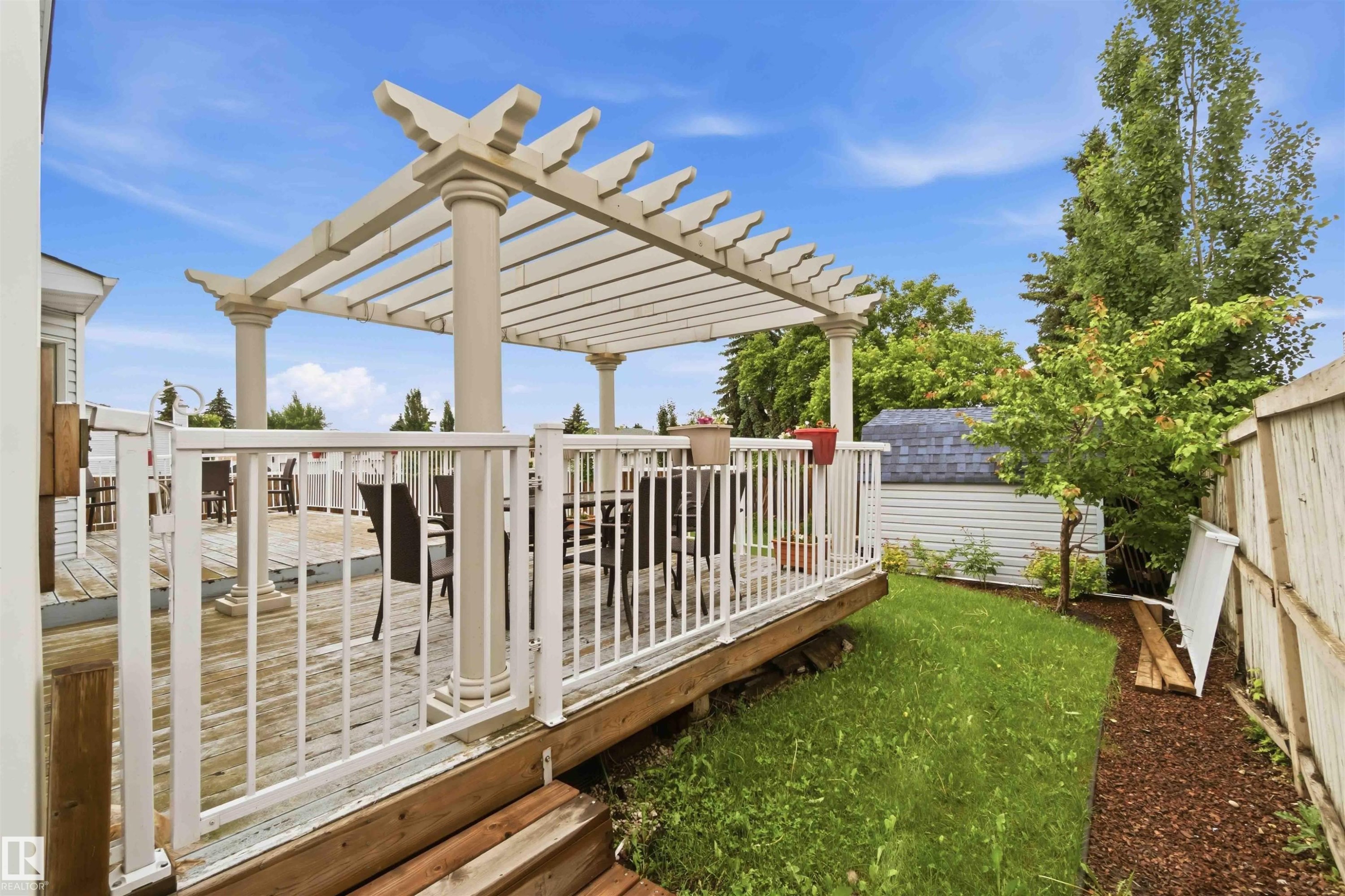 Expansive wood deck with a white pergola, white railings, and integrated steps - 4428 11A Avenue Nw, Edmonton, AB - Outdoor