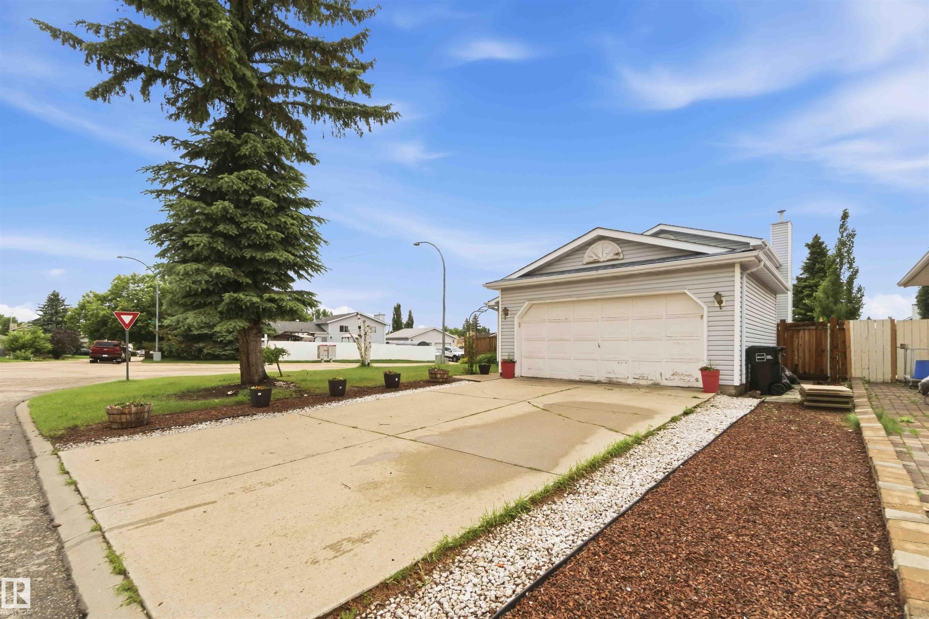 Exterior property featuring light-colored siding, an attached garage, and a concrete driveway - 4428 11A Avenue Nw, Edmonton, AB - Outdoor