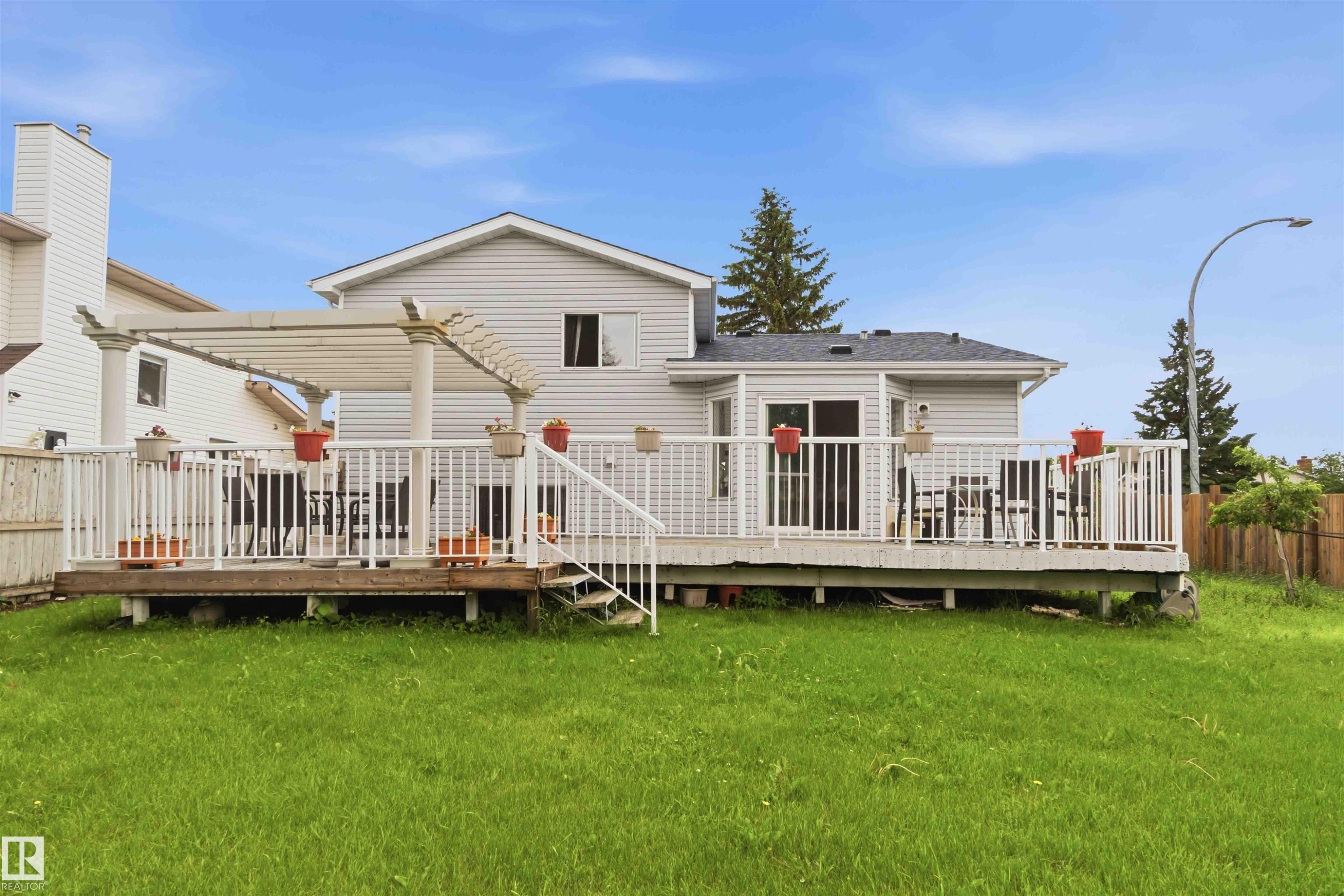 Expansive rear deck featuring white railings, a partial pergola structure, and direct access to the interior via a sliding glass door - 4428 11A Avenue Nw, Edmonton, AB - Outdoor With Deck Patio Veranda With Exterior