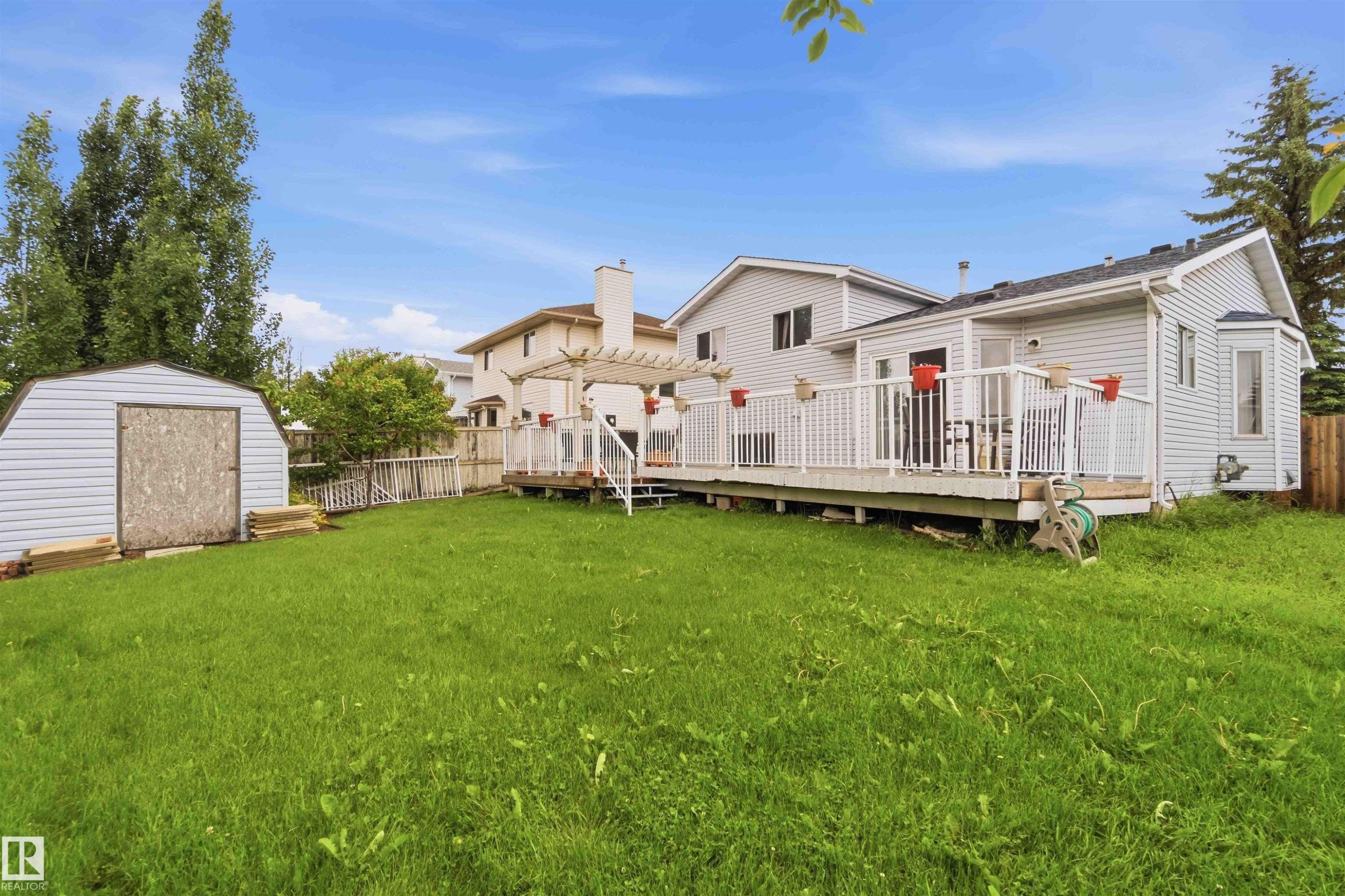 Spacious backyard featuring an elevated white deck, a pergola, a bay window, and a storage shed - 4428 11A Avenue Nw, Edmonton, AB - Outdoor With Deck Patio Veranda