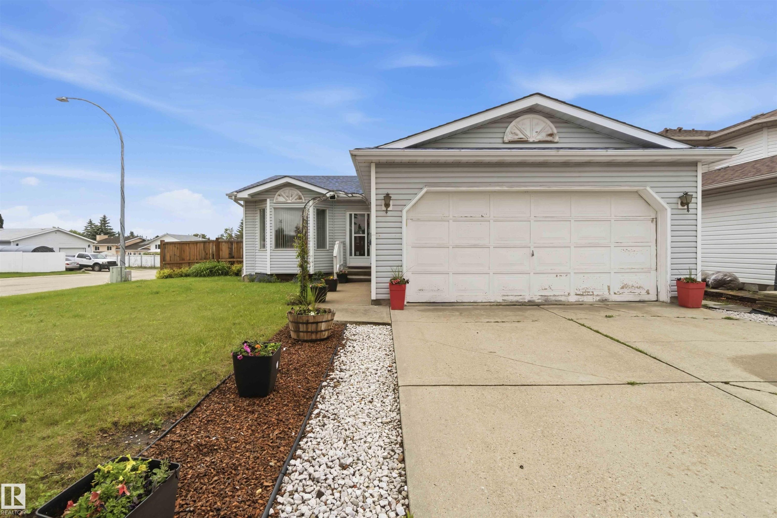 Front exterior featuring light-colored siding and an attached garage with a concrete driveway - 4428 11A Avenue Nw, Edmonton, AB - Outdoor