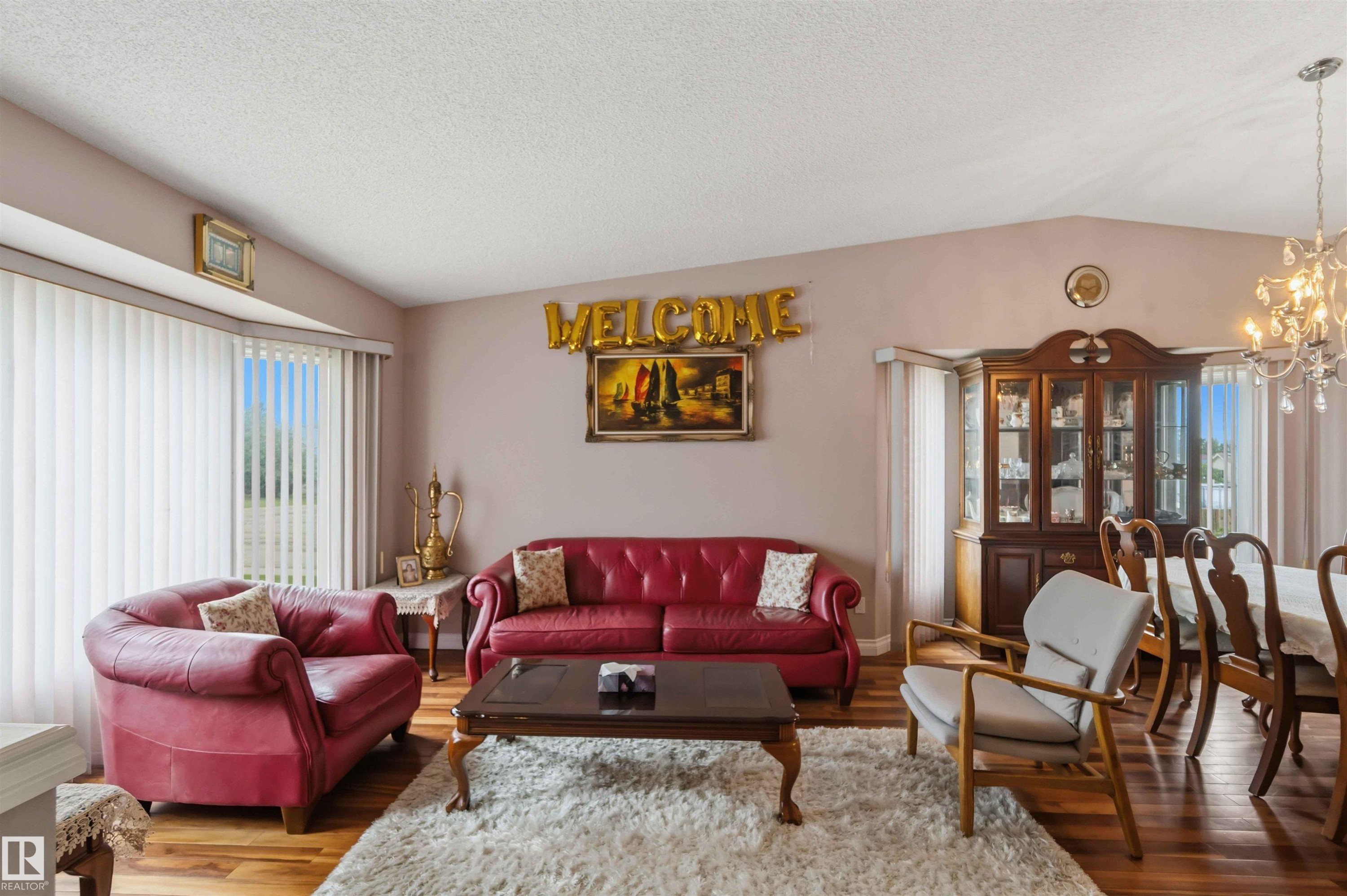Spacious living area featuring wood-finish flooring, a vaulted ceiling, and ample natural light from bay windows - 4428 11A Avenue Nw, Edmonton, AB - Indoor Photo Showing Living Room