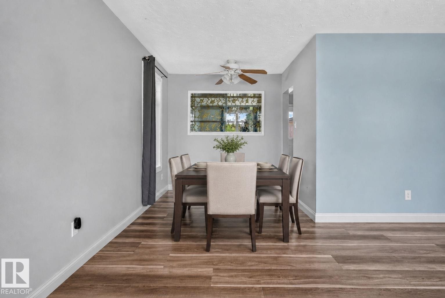 Dining area featuring wood-finish flooring, a white window frame, and a ceiling fan with light fixture - 13431 109 Street, Edmonton, AB