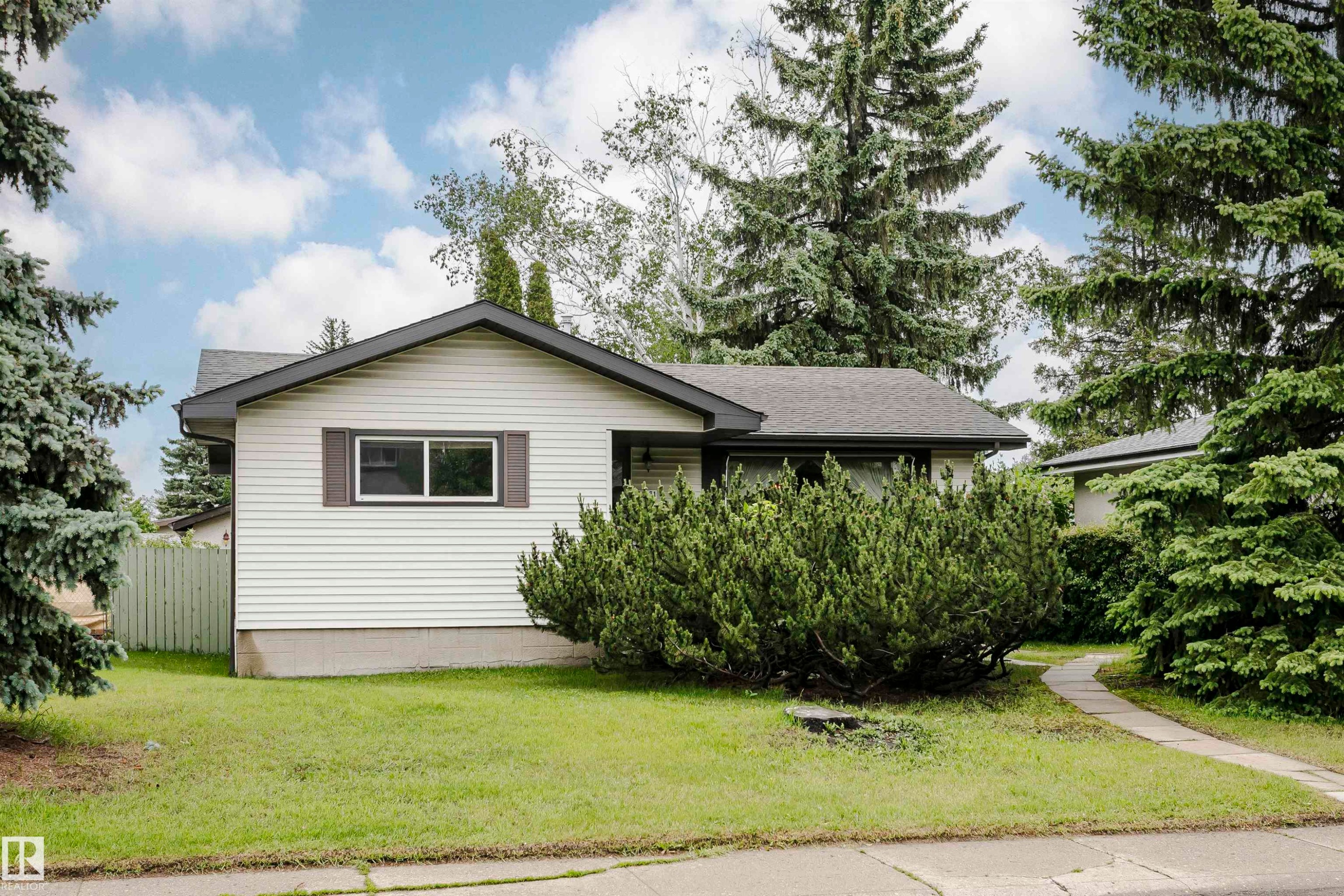 Single-story residence featuring white horizontal siding, a dark shingle roof, and a concrete pathway leading to the entrance - 14231 80 Street, Edmonton, AB