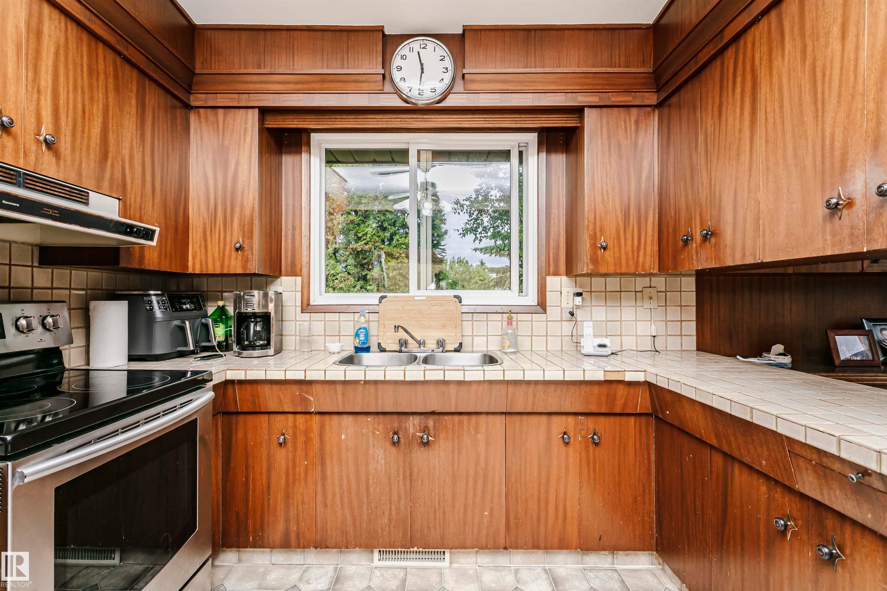 Kitchen featuring wood-finish cabinetry, a double basin sink, and a tiled countertop - 14231 80 Street, Edmonton, AB