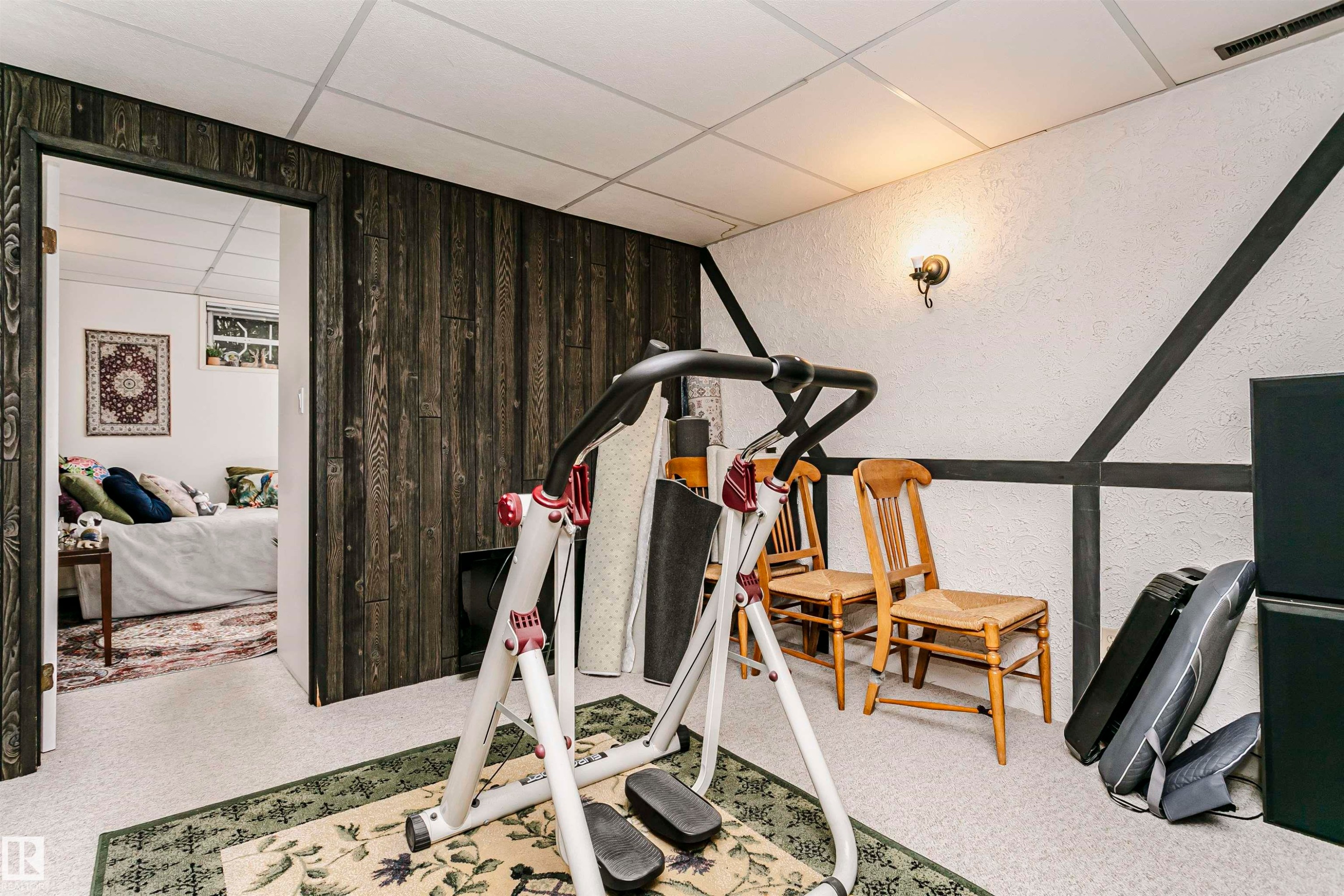 Finished lower level featuring textured walls with dark trim accents, plank-style wood-finish wall paneling, and wall-mounted sconce lighting - 14231 80 Street, Edmonton, AB