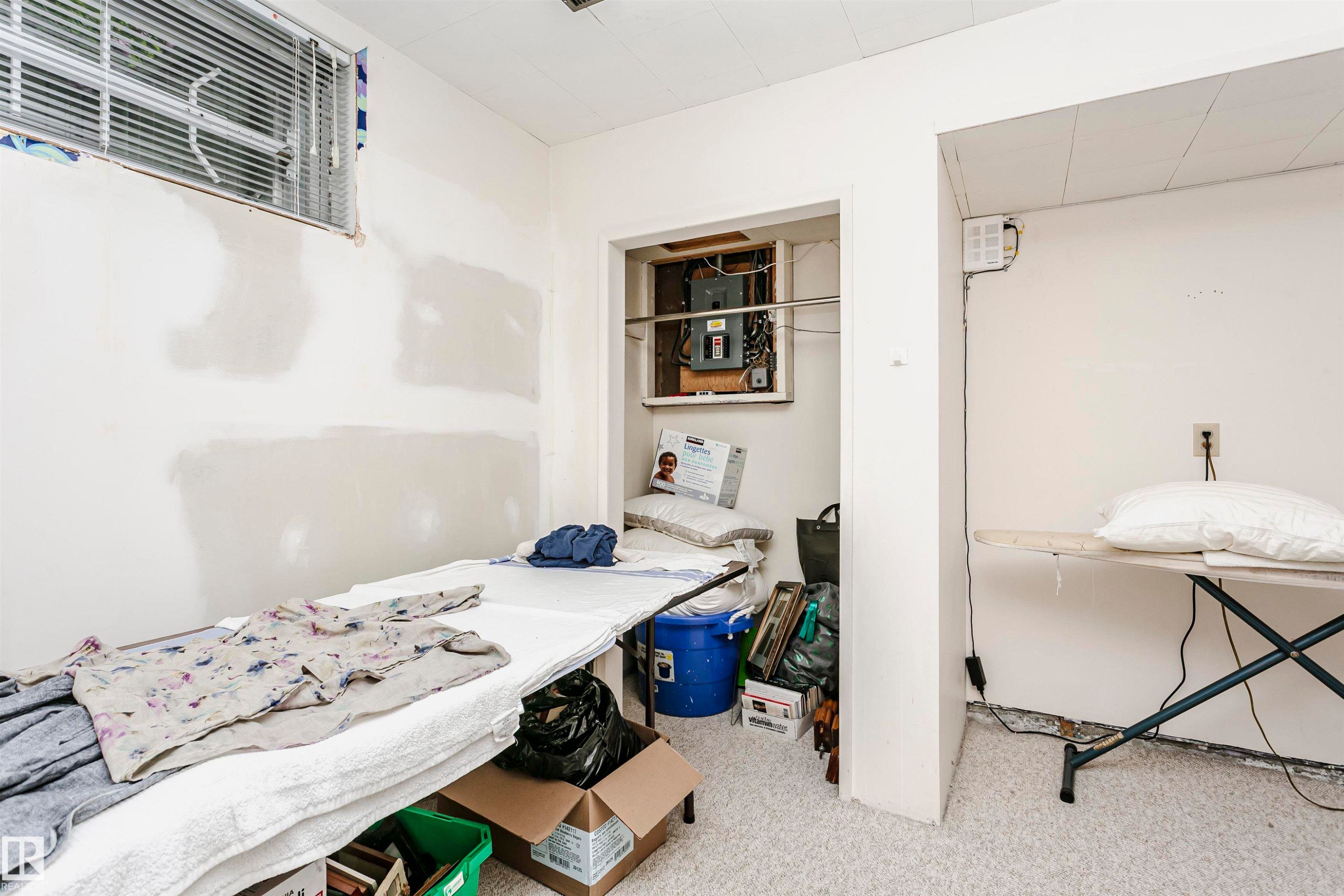 Unfinished interior space featuring a window with blinds, exposed electrical panel within an alcove, and light-colored flooring - 14231 80 Street, Edmonton, AB