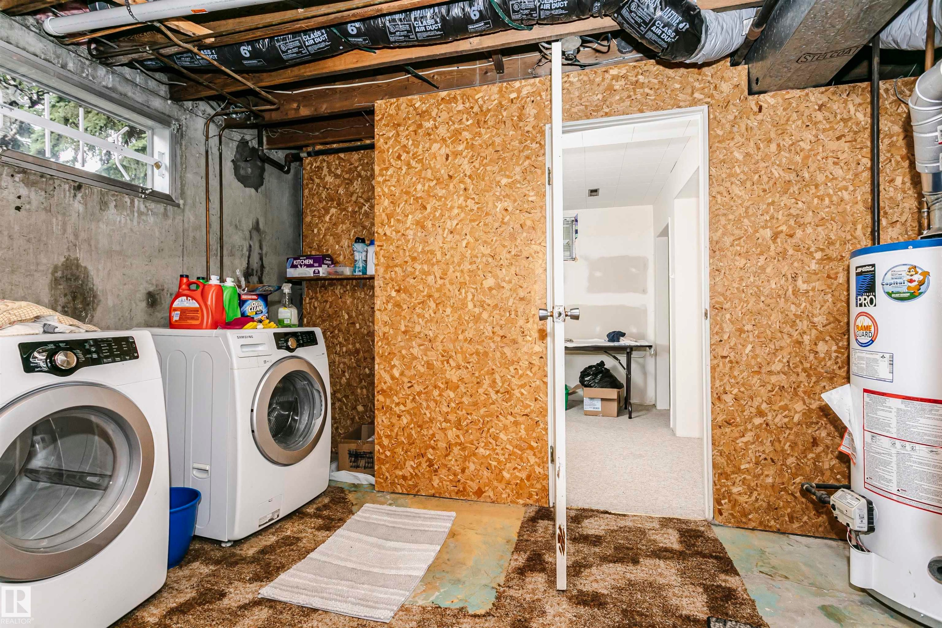 Utility area with exposed concrete walls, a single window, and visible overhead ductwork - 14231 80 Street, Edmonton, AB
