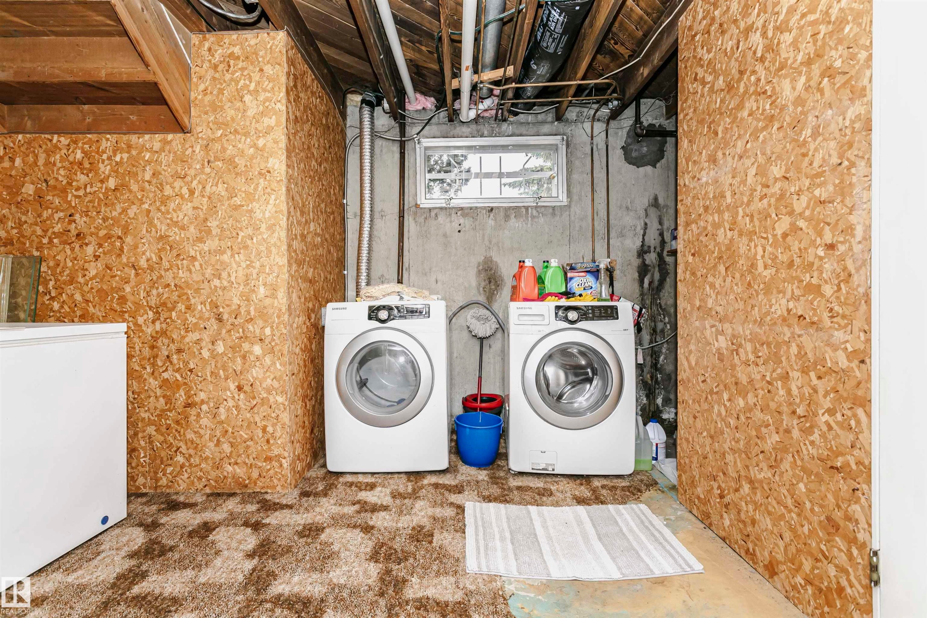Basement laundry area featuring a concrete wall, a small window, and exposed ceiling joists - 14231 80 Street, Edmonton, AB