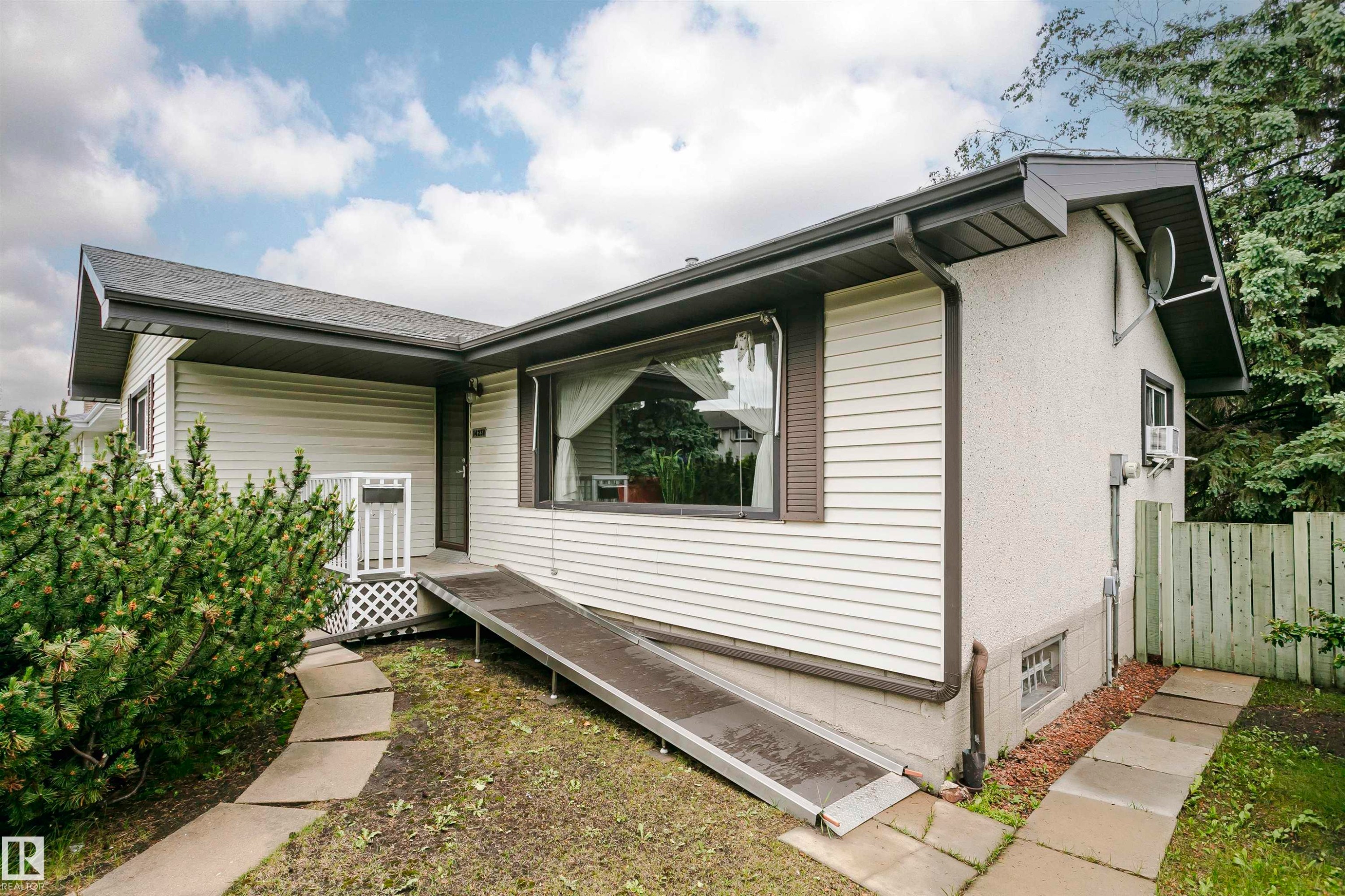 Single-story residence featuring light-colored siding and dark trim, gabled roofline, and a prominent front window - 14231 80 Street, Edmonton, AB