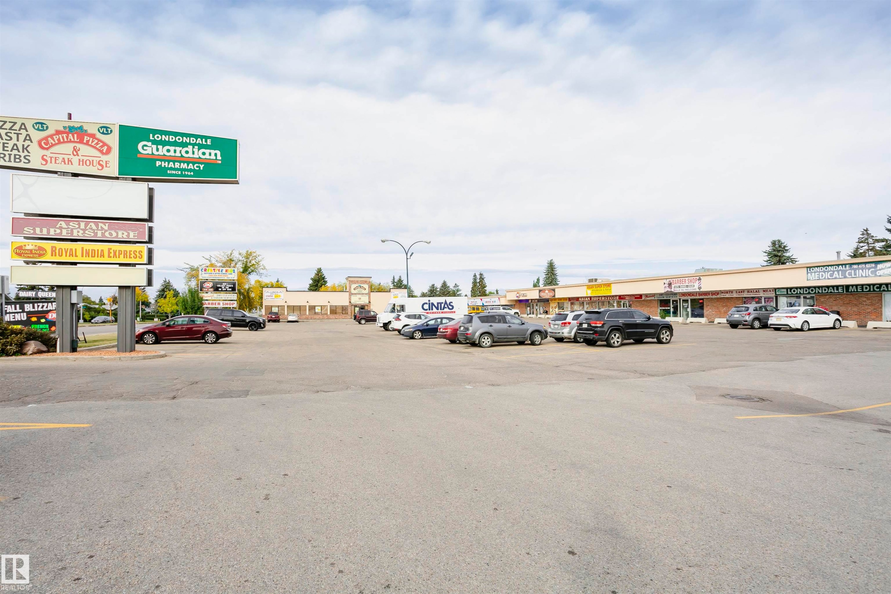 Commercial strip mall featuring multiple retail units, a prominent pylon sign, and a paved parking lot - 14231 80 Street, Edmonton, AB