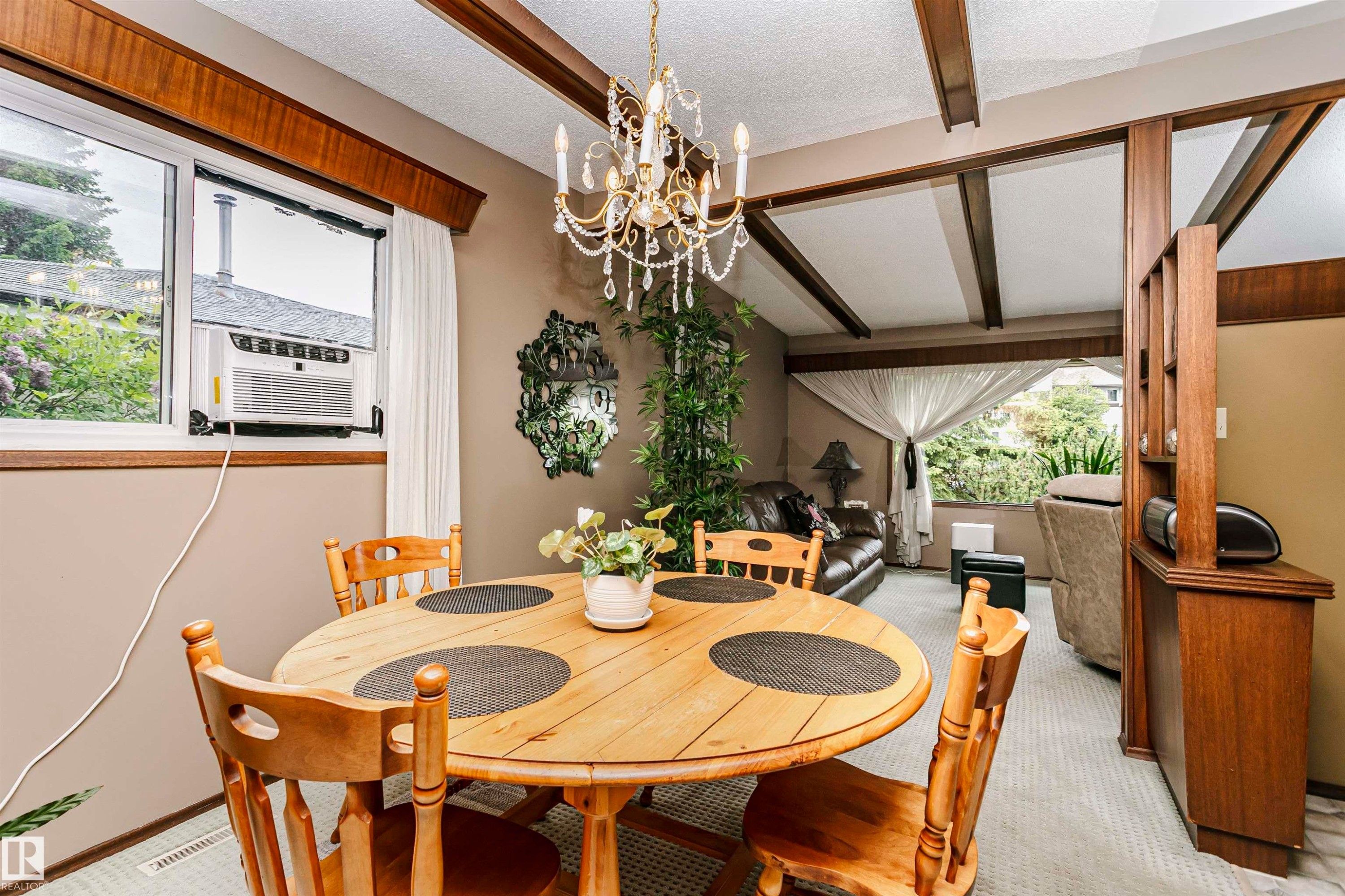 Dining area featuring a wood-finish round table and chairs, illuminated by a chandelier with crystal accents - 14231 80 Street, Edmonton, AB