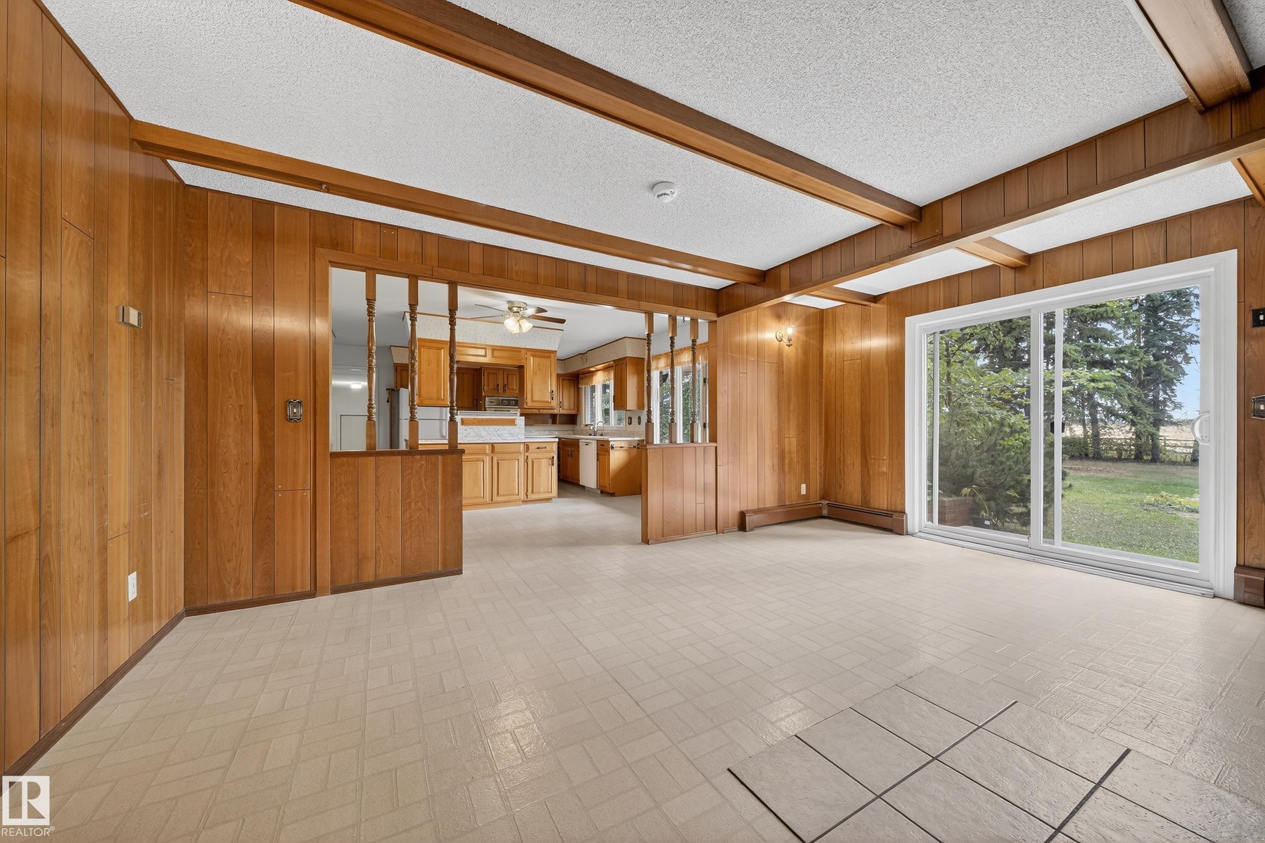Interior space featuring wood paneling, exposed wood ceiling beams, and light-toned tile flooring - 707 65 Avenue, Edmonton, AB