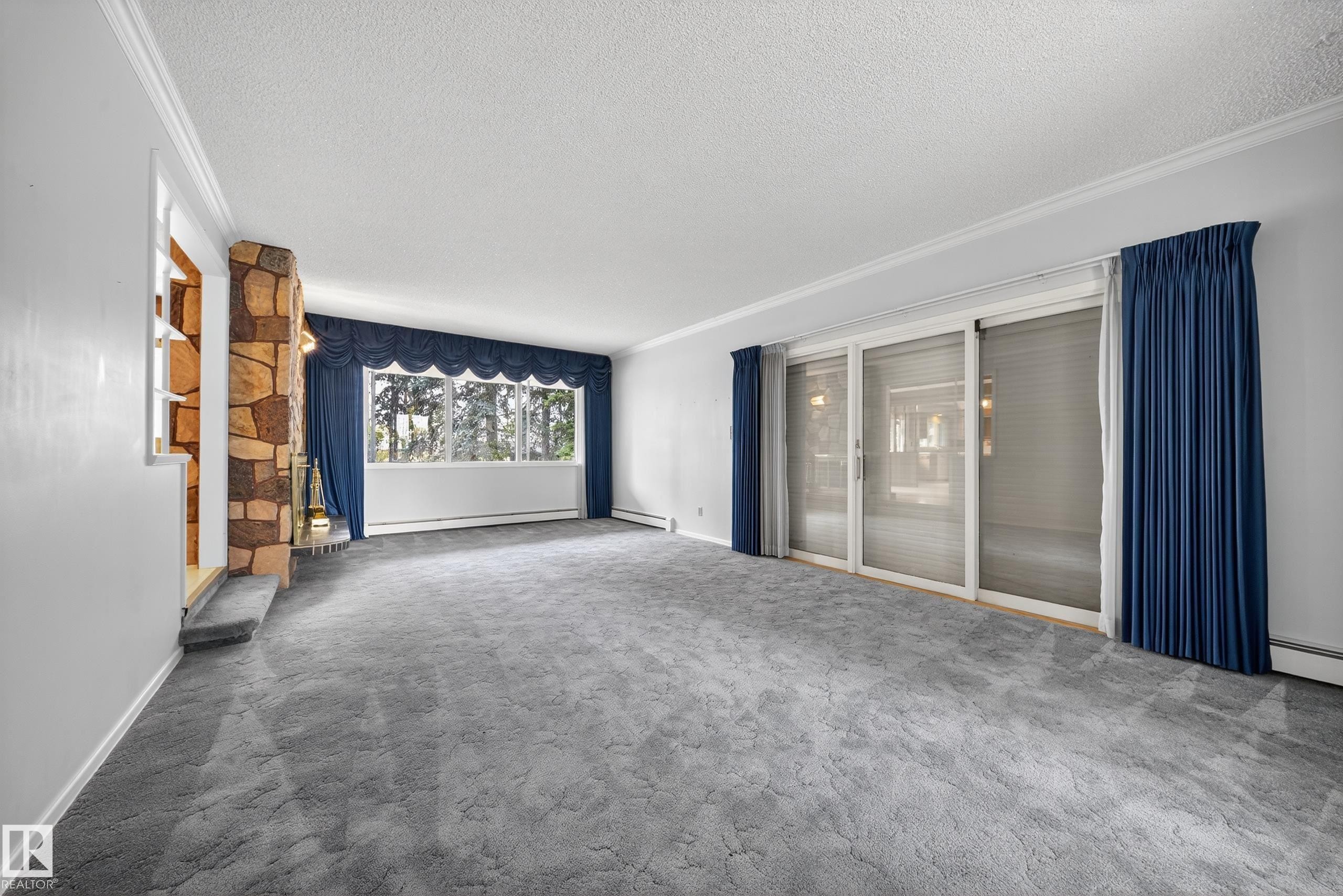 Spacious living area featuring a stone-clad fireplace and large sliding glass doors - 707 65 Avenue, Edmonton, AB