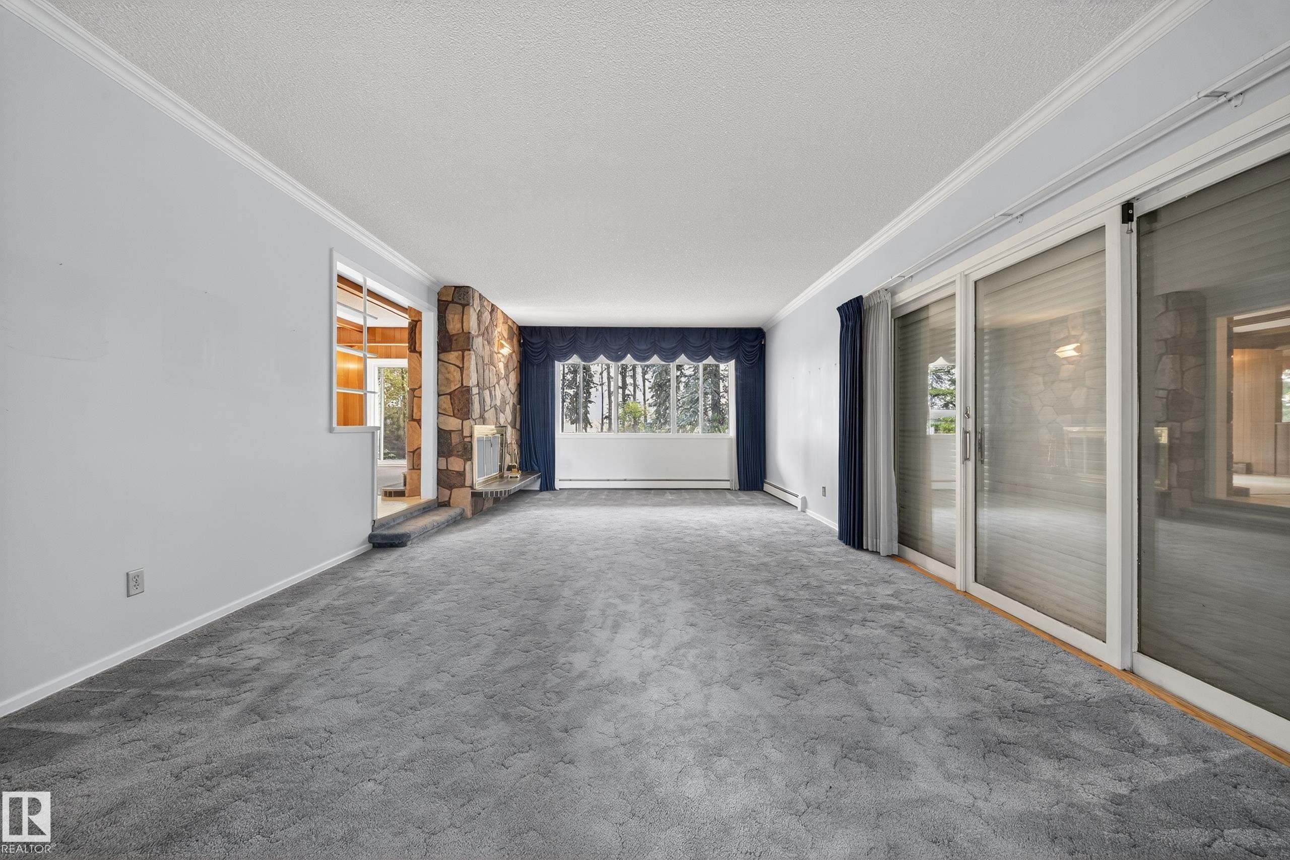 Living area featuring a stone fireplace, broad picture window, and sliding glass doors - 707 65 Avenue, Edmonton, AB