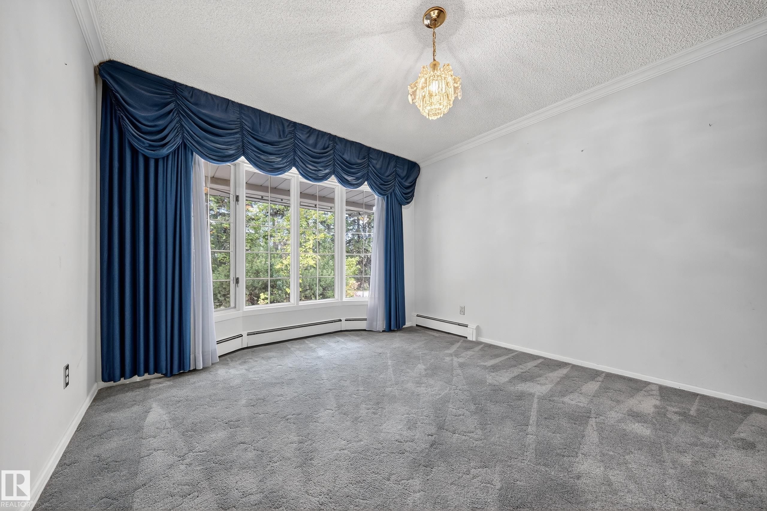 Bay window with blue drapery, gray patterned carpet, crown molding, and a crystal chandelier - 707 65 Avenue, Edmonton, AB