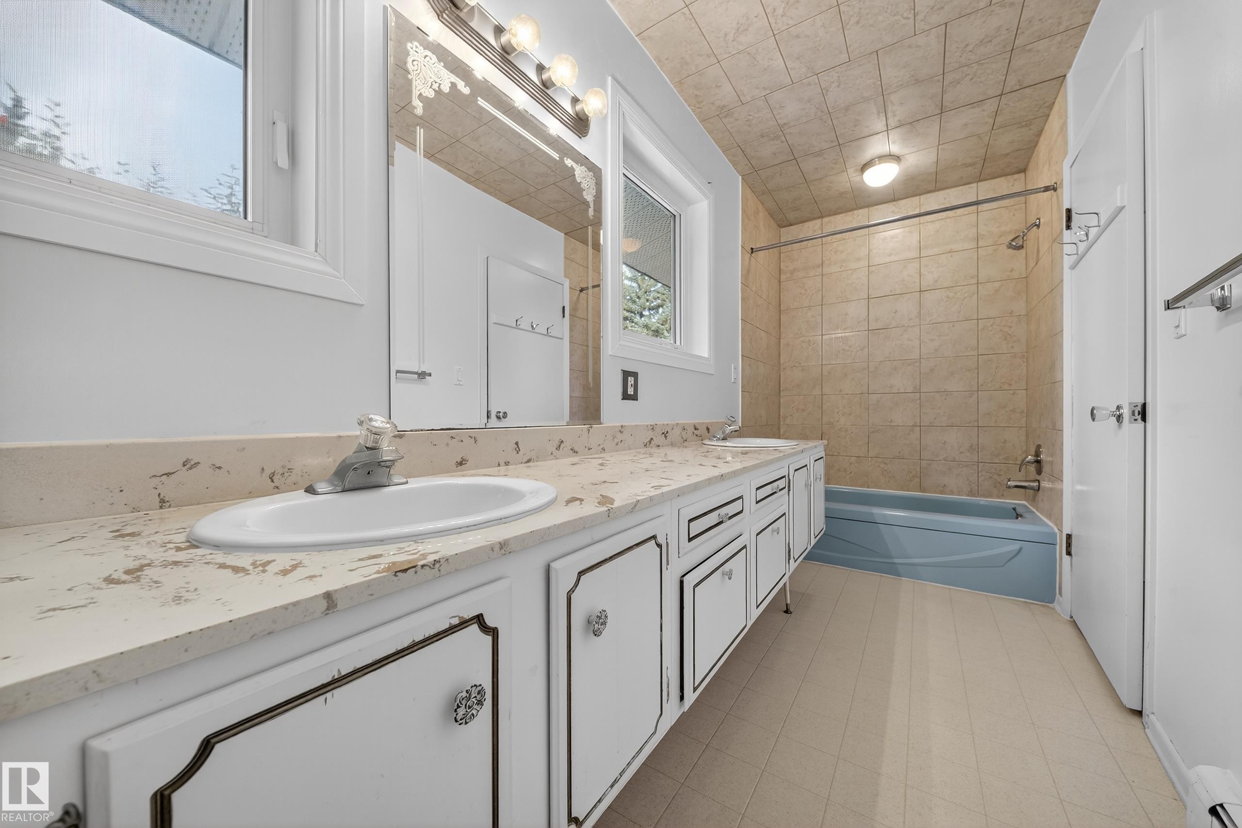 Bathroom featuring a double vanity with stone-finish countertop, dual sinks, and white cabinetry - 707 65 Avenue, Edmonton, AB
